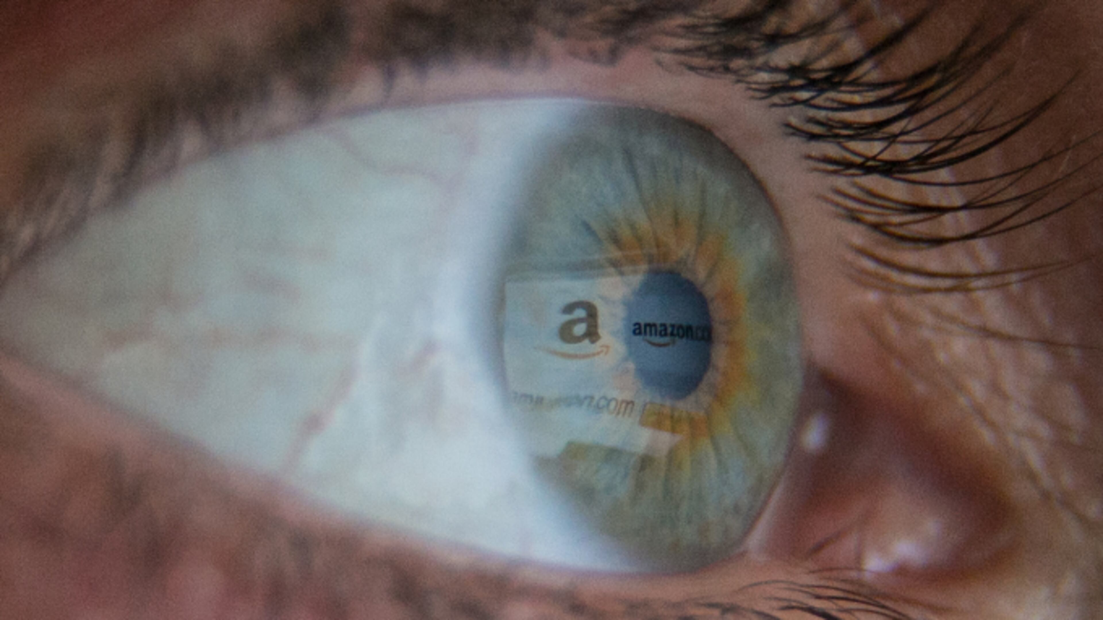 In this photo illustration a woman has the online retailer Amazon logo reflected in her eye as she shops online.