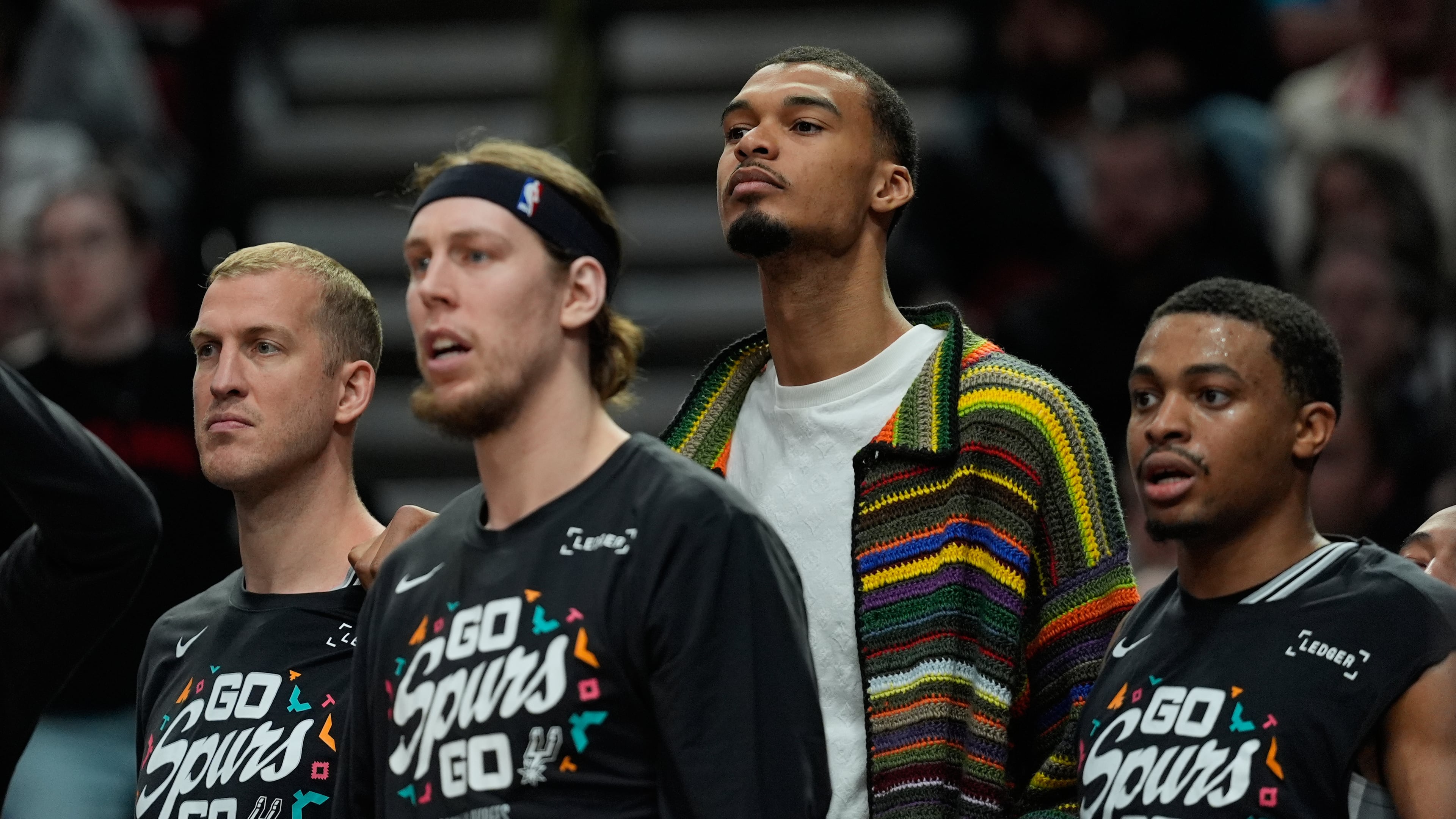 San Antonio Spurs forward Victor Wembanyama, center, wears street cloths on the bench as he sits out Game 3 of a first-round NBA playoffs basketball series against the Portland Trail Blazers in Portland, Ore, Friday, April 24, 2026. (AP Photo/Jenny Kane)