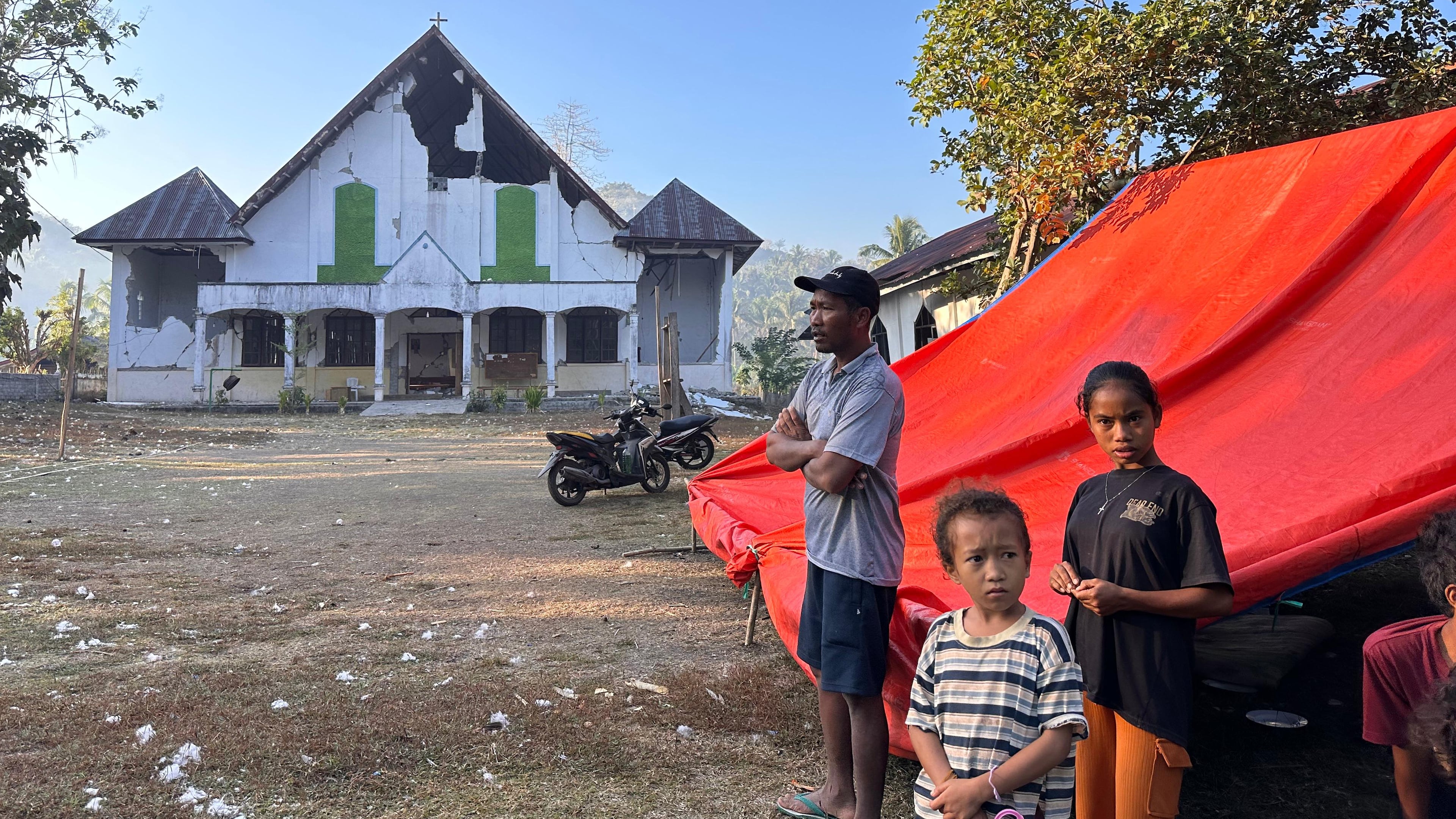 Earthquake survivors stand outside their tent erected near a damaged church in Satar Punda, East Nusa Tenggara province, Indonesia, Tuesday, Aug. 18, 2026. (AP Photo/Firdia Lisnawati)