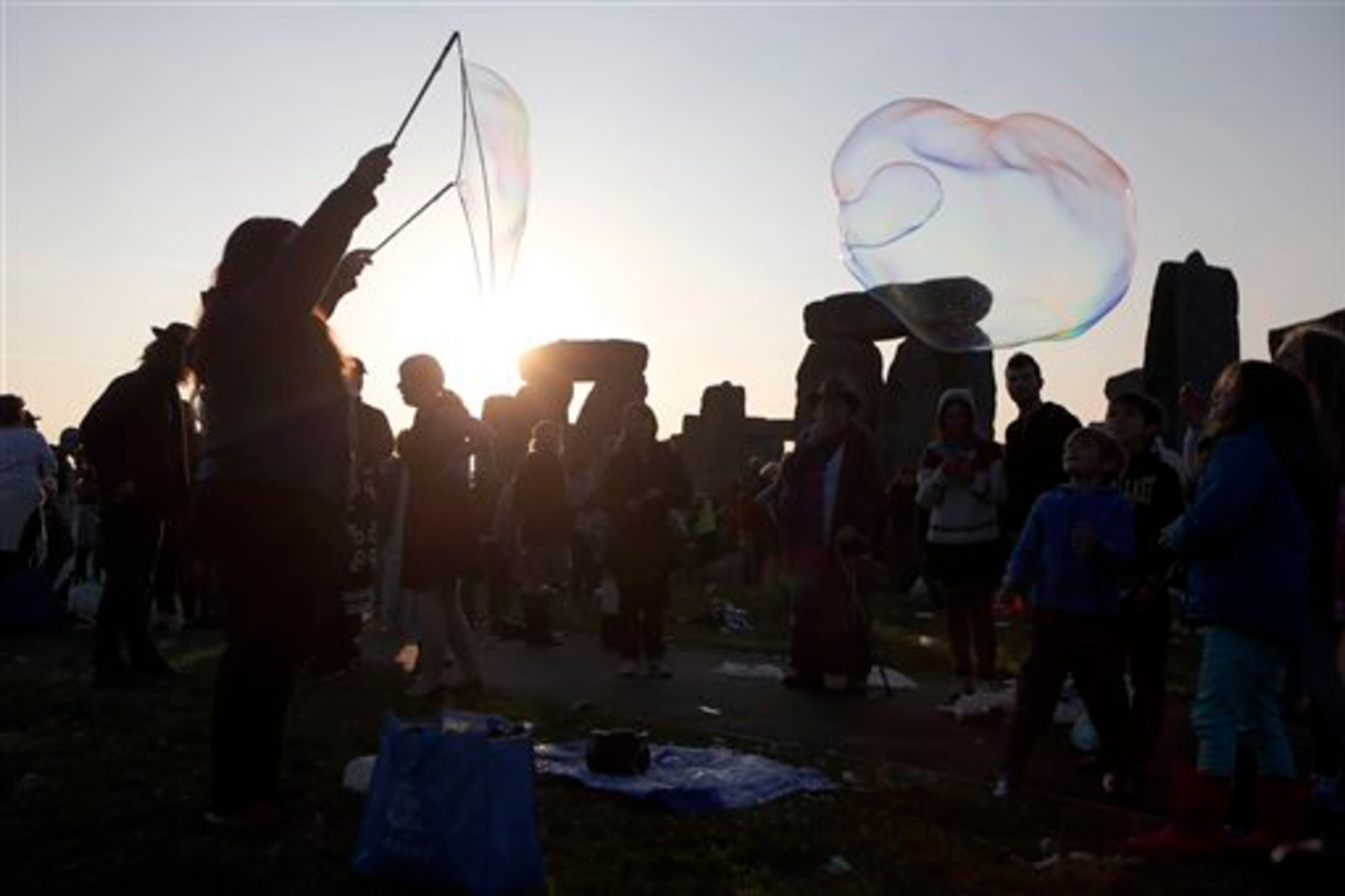 A reveler makes giant bubble as thousands gathered at the ancient stone circle Stonehenge, near Salisbury, England, to celebrate the summer solstice, the longest day of the year, Saturday, June 21, 2014. (AP Photo/Sang Tan)