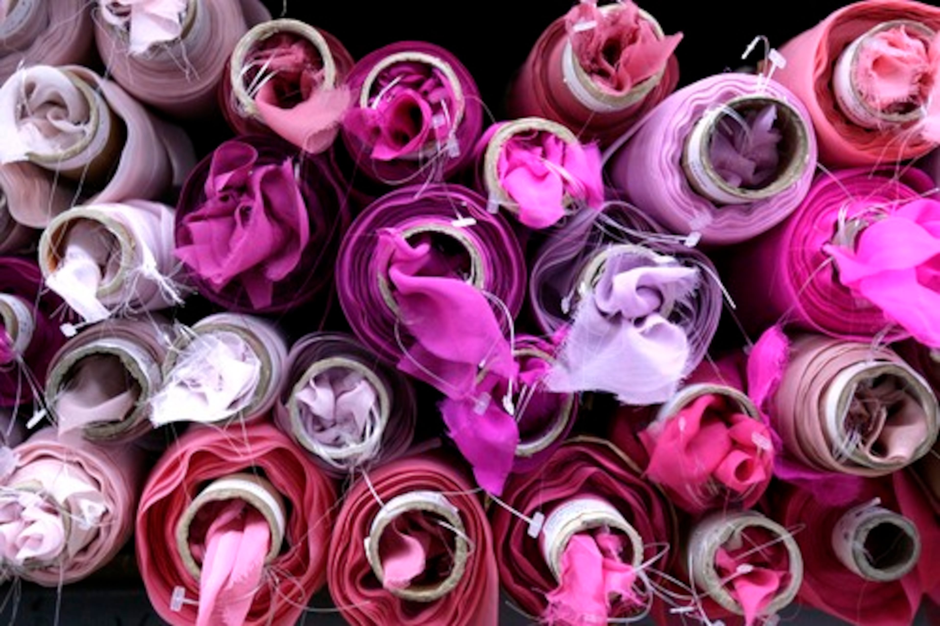 Diaphanous material in various shades of pink and orchid is gathered in puffs at the ends of rolls stacked on shelves at Elegant Fabrics in New York's garment district.