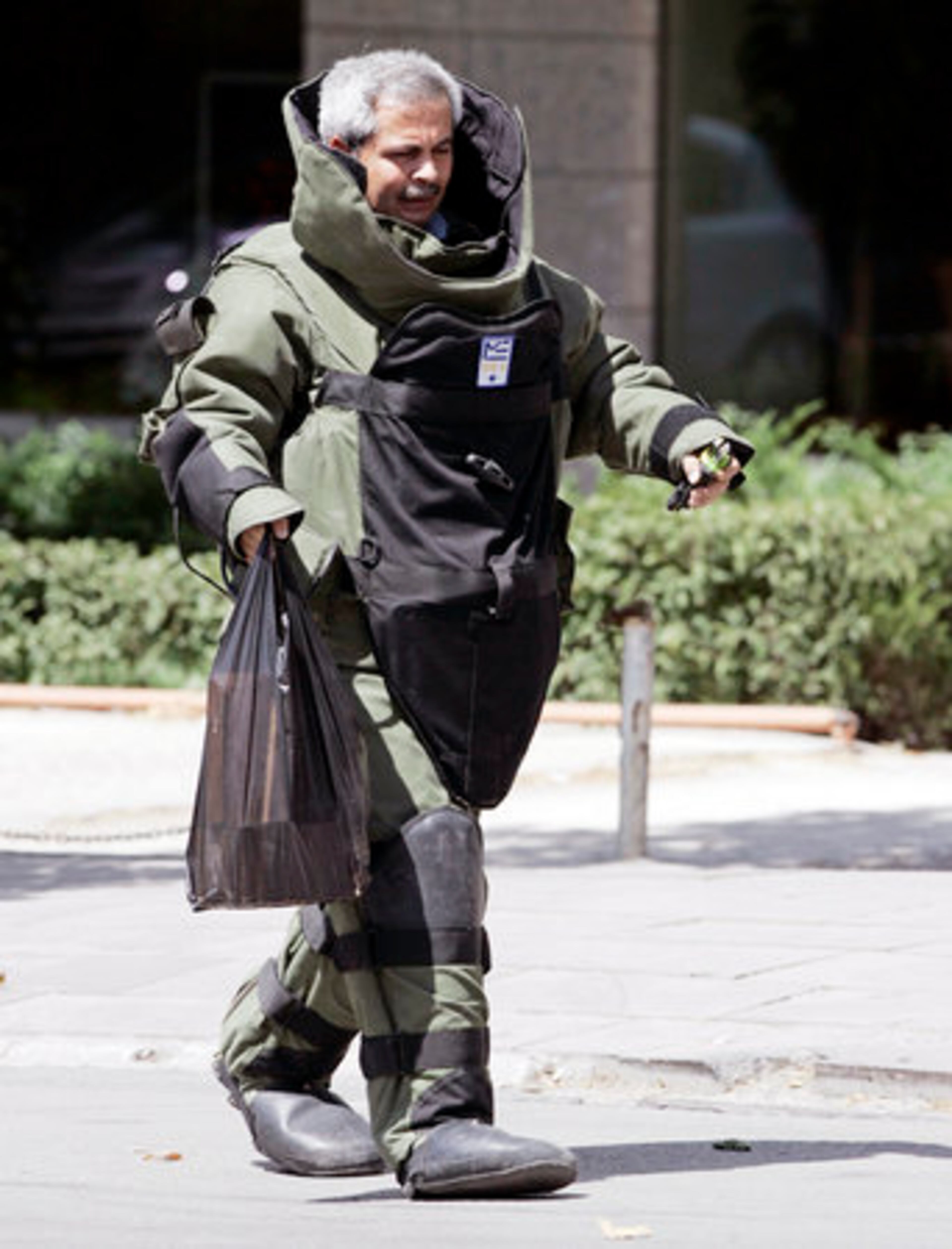 A bomb expert of the Turkish police carries a suspected parcel after he checked it with a remote-controlled robot in the city center in Ankara, Wednesday. Men armed with pistols and shotguns attacked a police guard post outside the U. S. consulate in Istanbul, sparking a gunbattle that left three officers and three attackers dead.