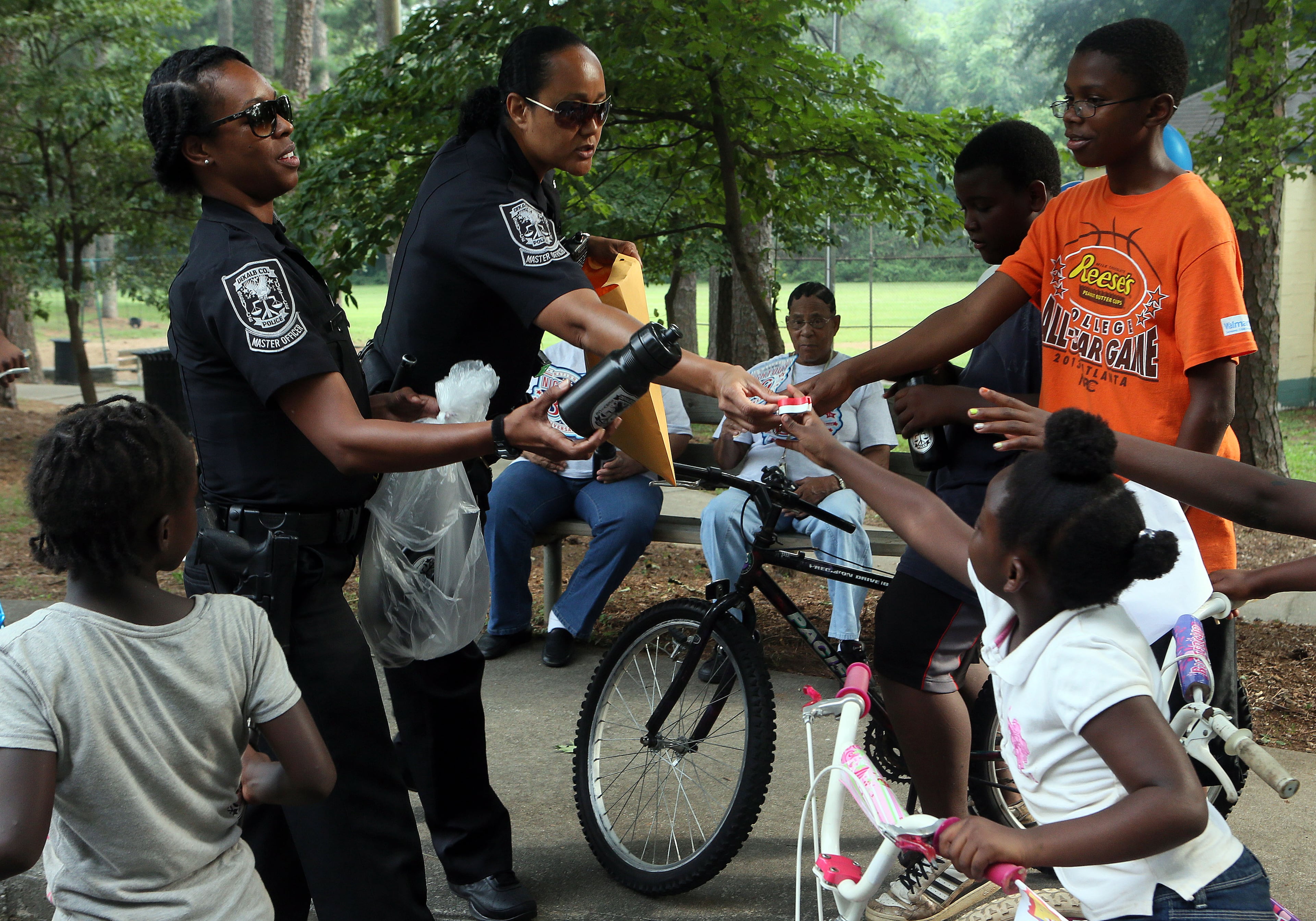 Dekalb Master Officers T.V Linsey (left) & B. Hooker handed out freebees at the Parkview Community Recreational Center in Atlanta during the 30th anniversary of National Night Out on Tuesday. Atlanta Police Chief George N. Turner visited all 10 Atlanta community parties addressing crime prevention.