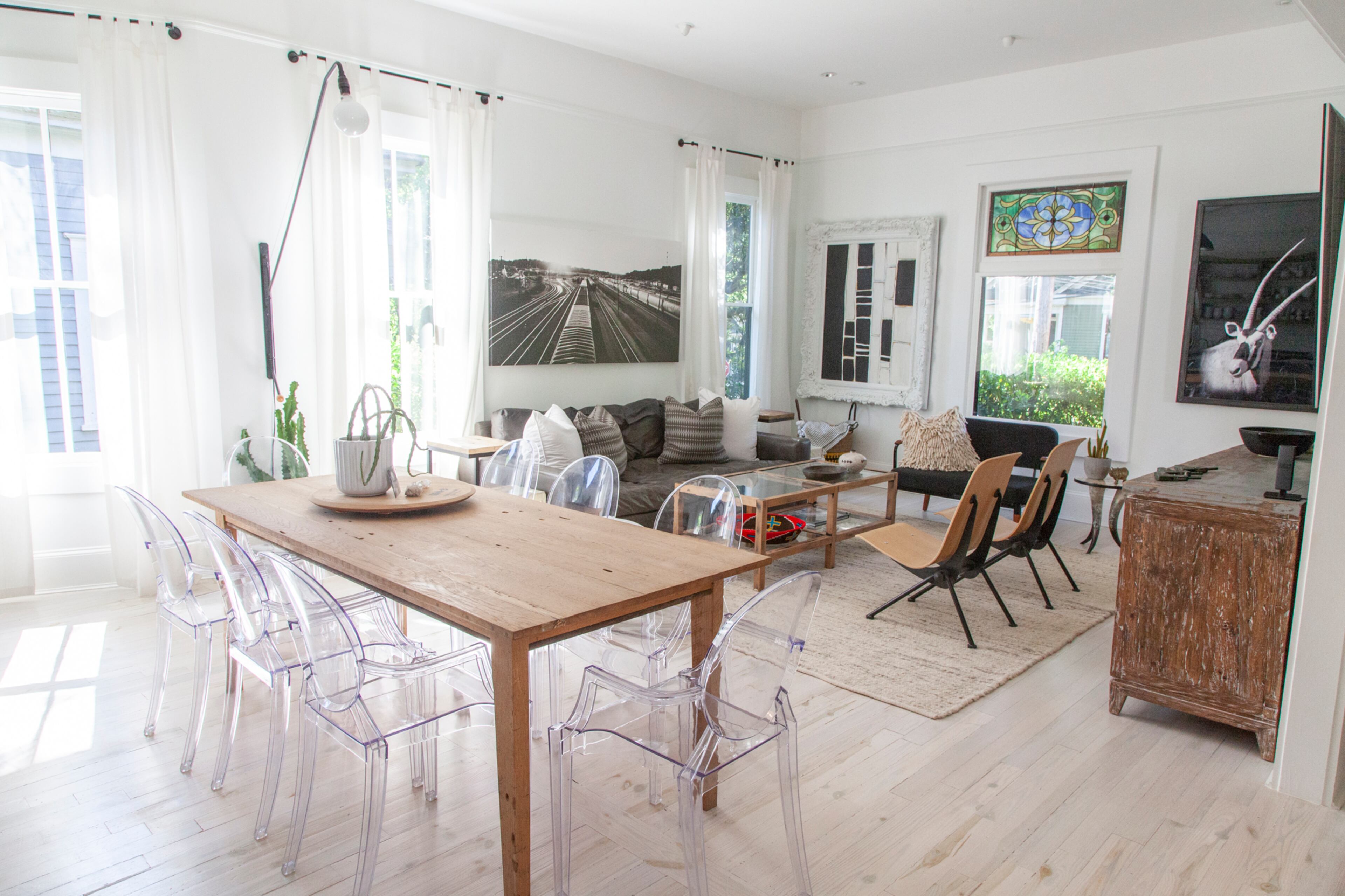 The art-filled home includes the framed black and white piece by homeowner Alyssa Cassatto. A friend's photograph of an Atlanta train yard hangs over the couch from Stanton Home Furnishings. The wooden chairs are from France & Son, and the settee is from Industry West. The coffee table is repurposed; it originally was black.