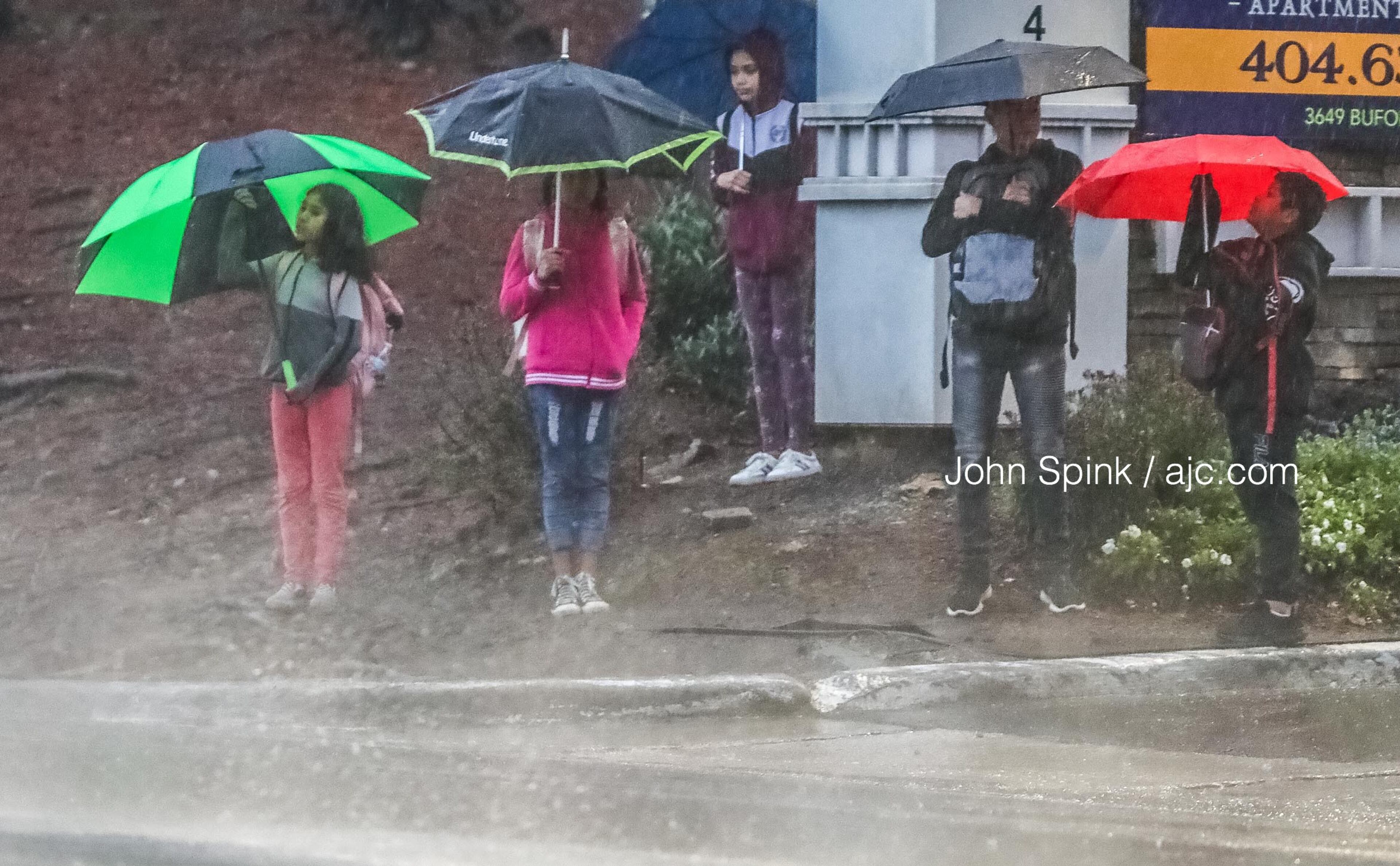 Students wait for their school bus in the rain in the 3600 block of Buford Highway in DeKalb County.