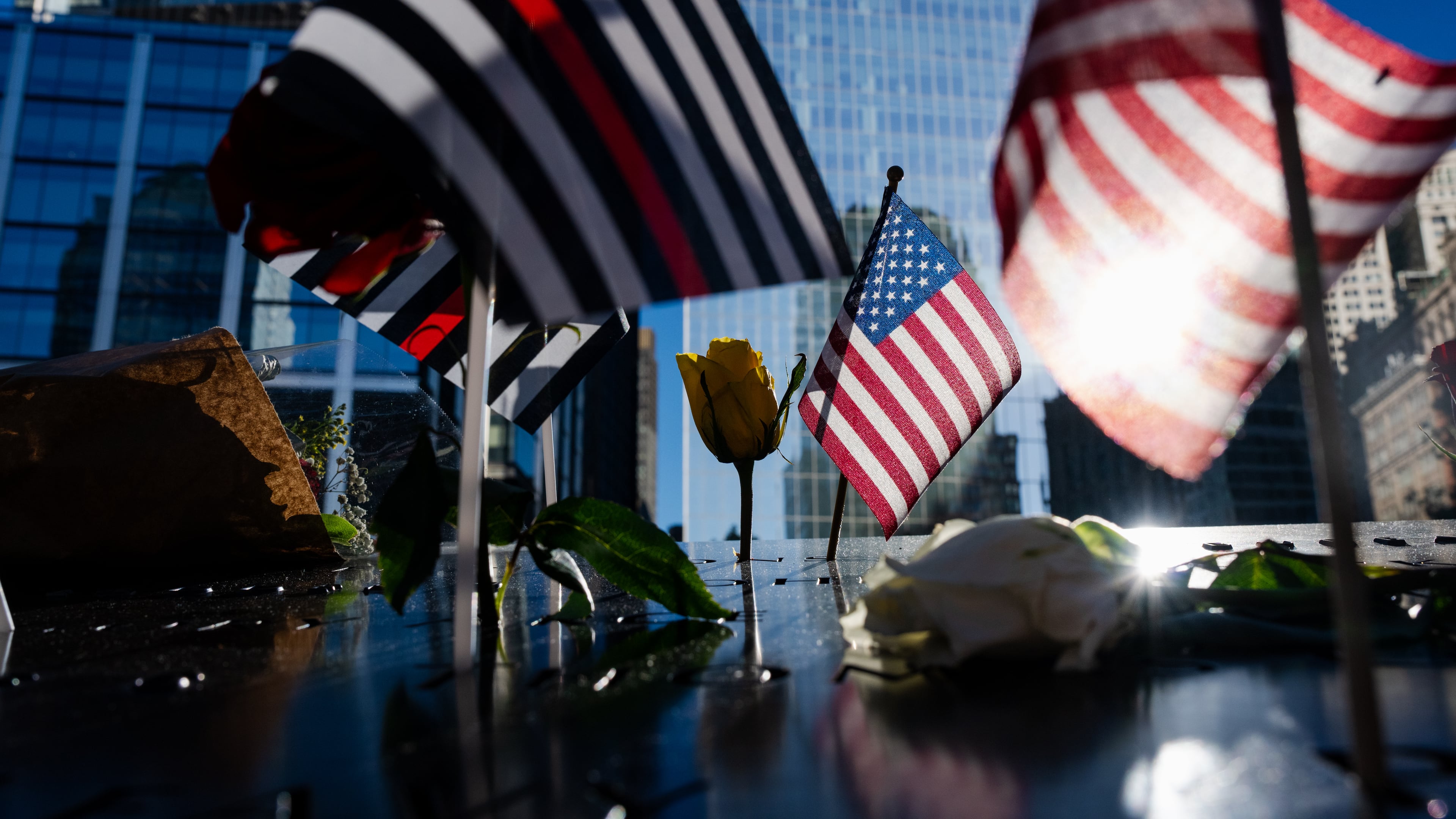 Flags and roses are placed on the edge of the 9/11 Memorial Pools on the 25th anniversary of the September 11 World Trade Center attacks, Friday, Sept. 11, 2026, in New York. (AP Photo/Angelina Katsanis)