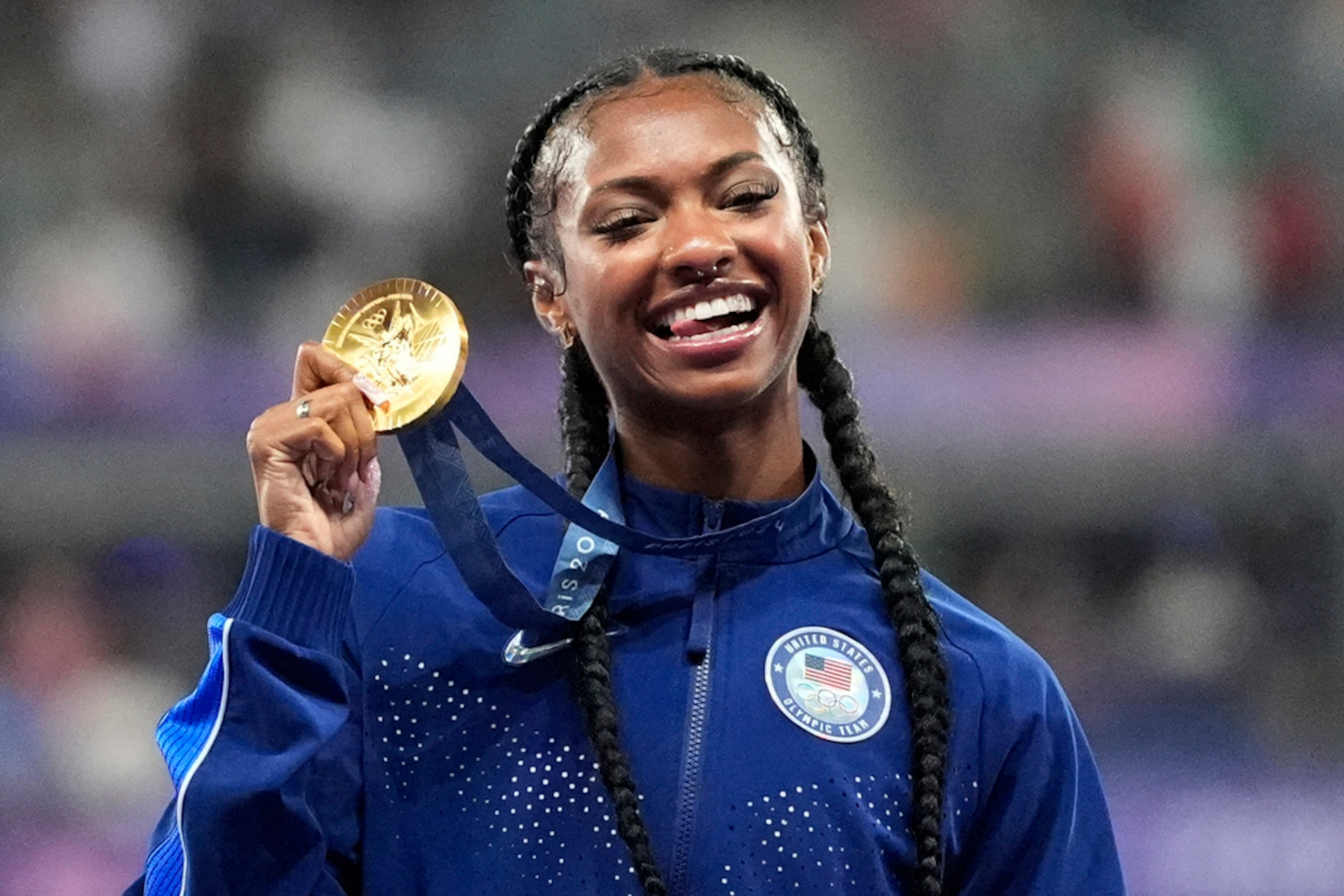 Women's 100-meter hurdles gold medalist Masai Russell, of the United States, smiles on the podium at the 2024 Summer Olympics, Saturday, Aug. 10, 2024, in Saint-Denis, France. (AP Photo/Matthias Schrader)