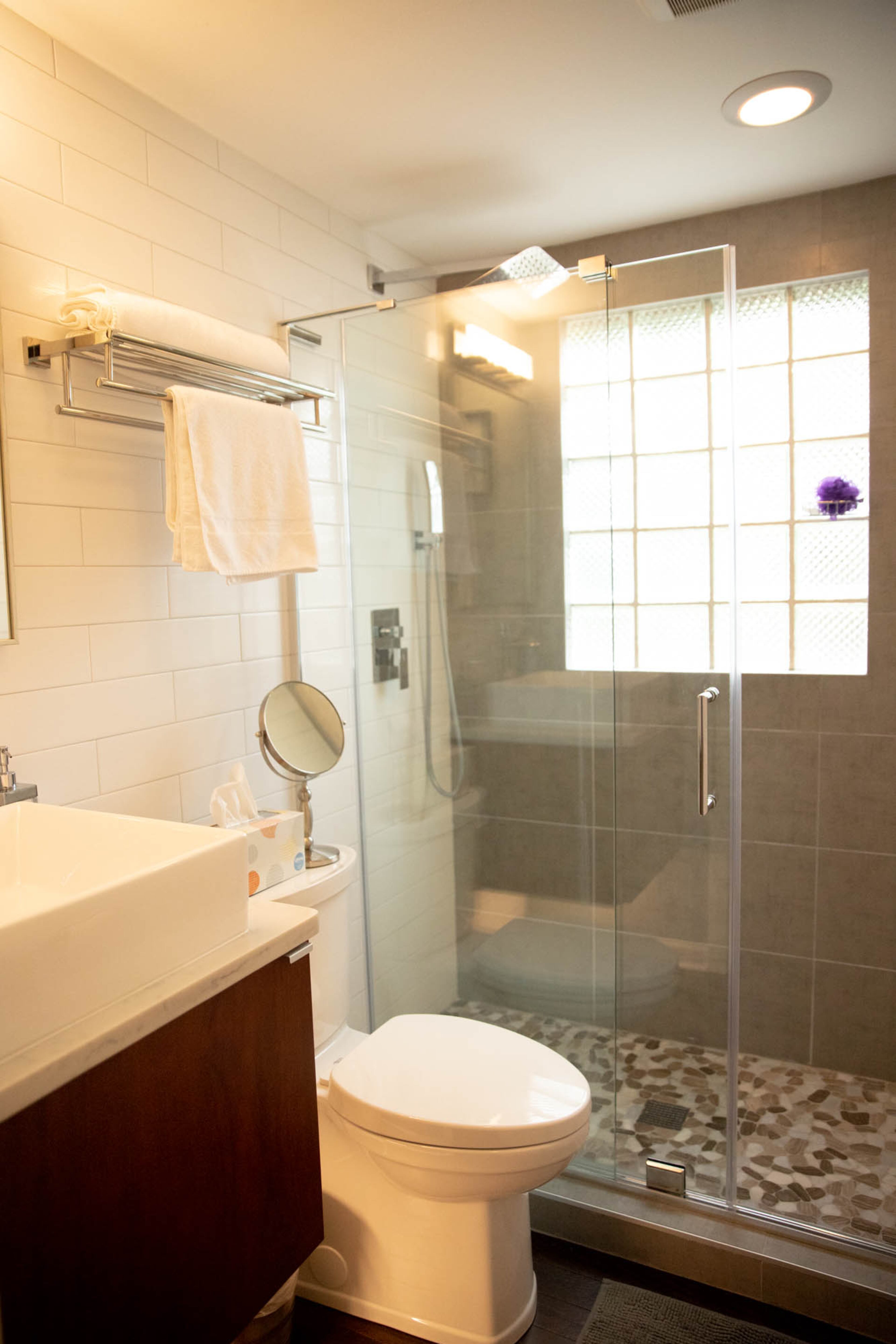 Subway tile from The Tile Shop along with contempo evolution tiles and pebble moonlight mosaic shower floor tile from Floor & Decor give the downstairs shower in Adam Perry and Ben Ratossa's home a signature look without exceeding the bathroom's original footprint.