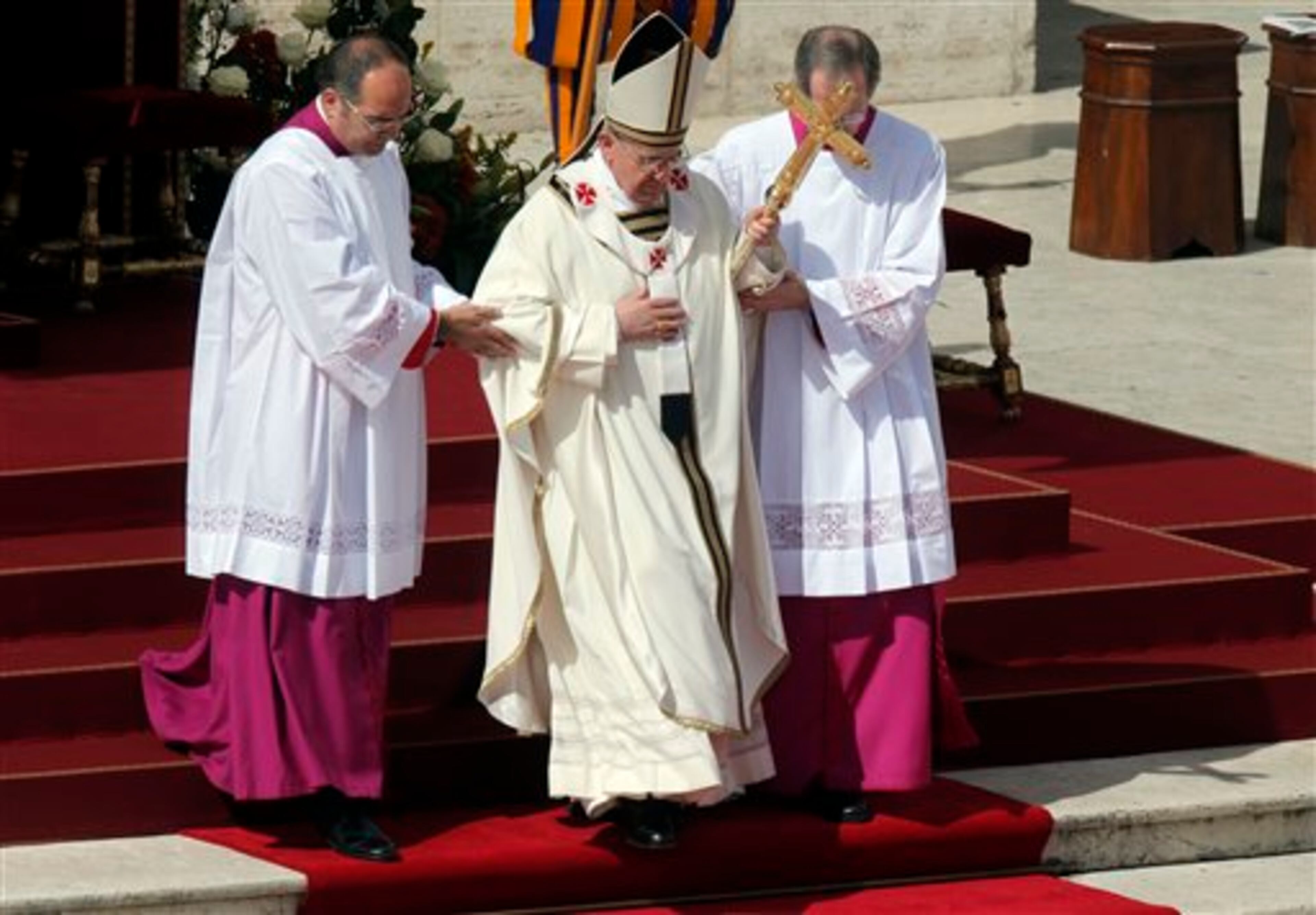 Pope Francis is helped walk down the steps in St. Peter's Square at the Vatican, Tuesday, March 19, 2013. Pope Francis has urged princes, presidents, sheikhs and thousands of ordinary people gathered for his installation Mass to protect God's creation, the weakest and the poorest of the world. (AP Photo/Dmitry Lovetsky)