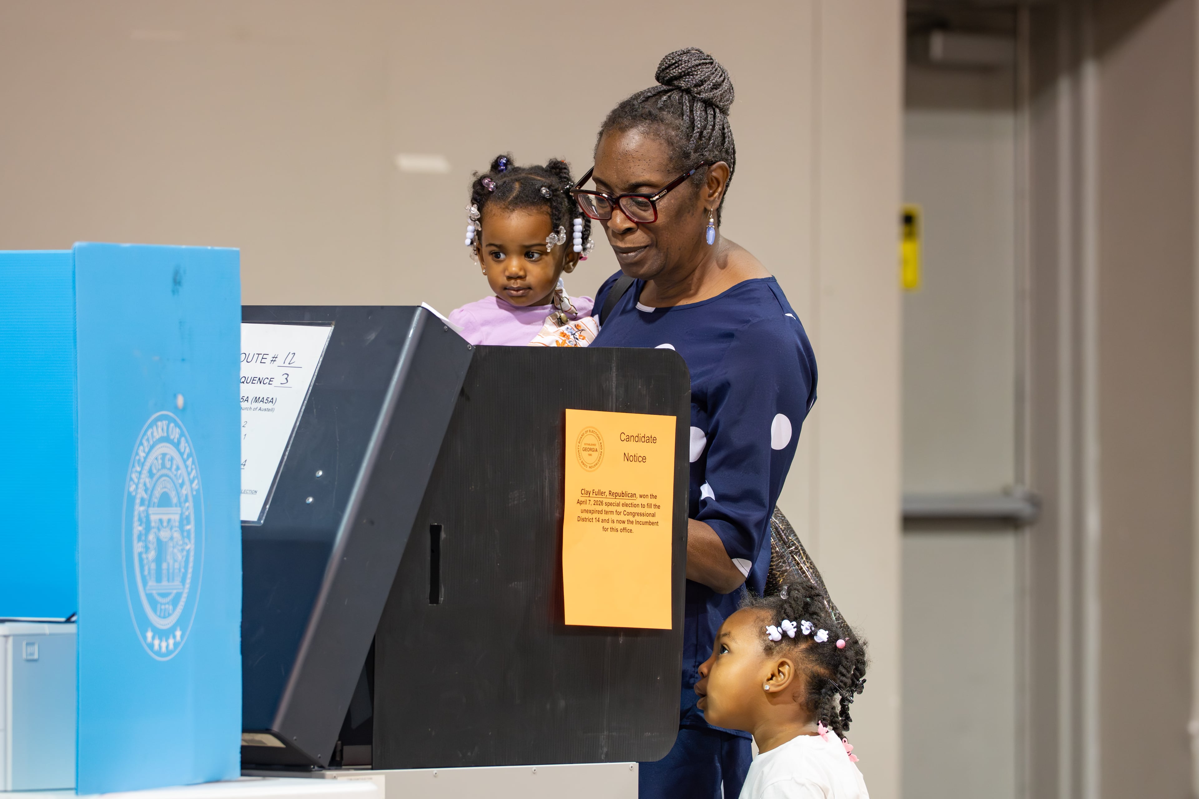 A woman holds a child while voting at the Calvary Baptist Church polling location in Austell, Georgia. Tuesday, May 19, 2026 (Ben Hendren for the AJC)