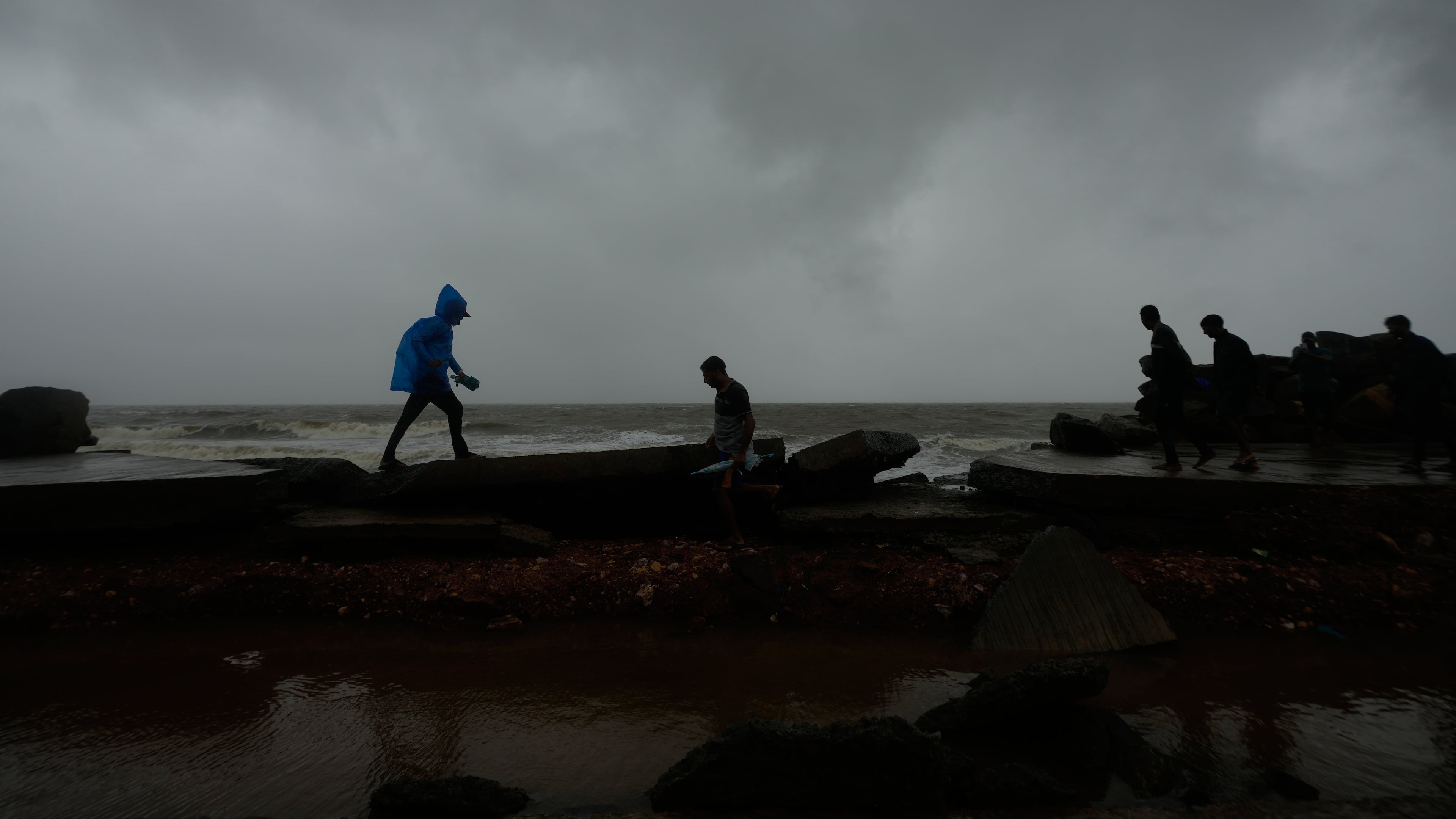 People walk on a damaged road near the shore in Uppada, Kakinada, India, Wednesday, Oct. 28, 2026, after Cyclone Arnab crossed the Andhra Pradesh coast earlier in the day. (AP Photo/Mahesh Kumar A.)
