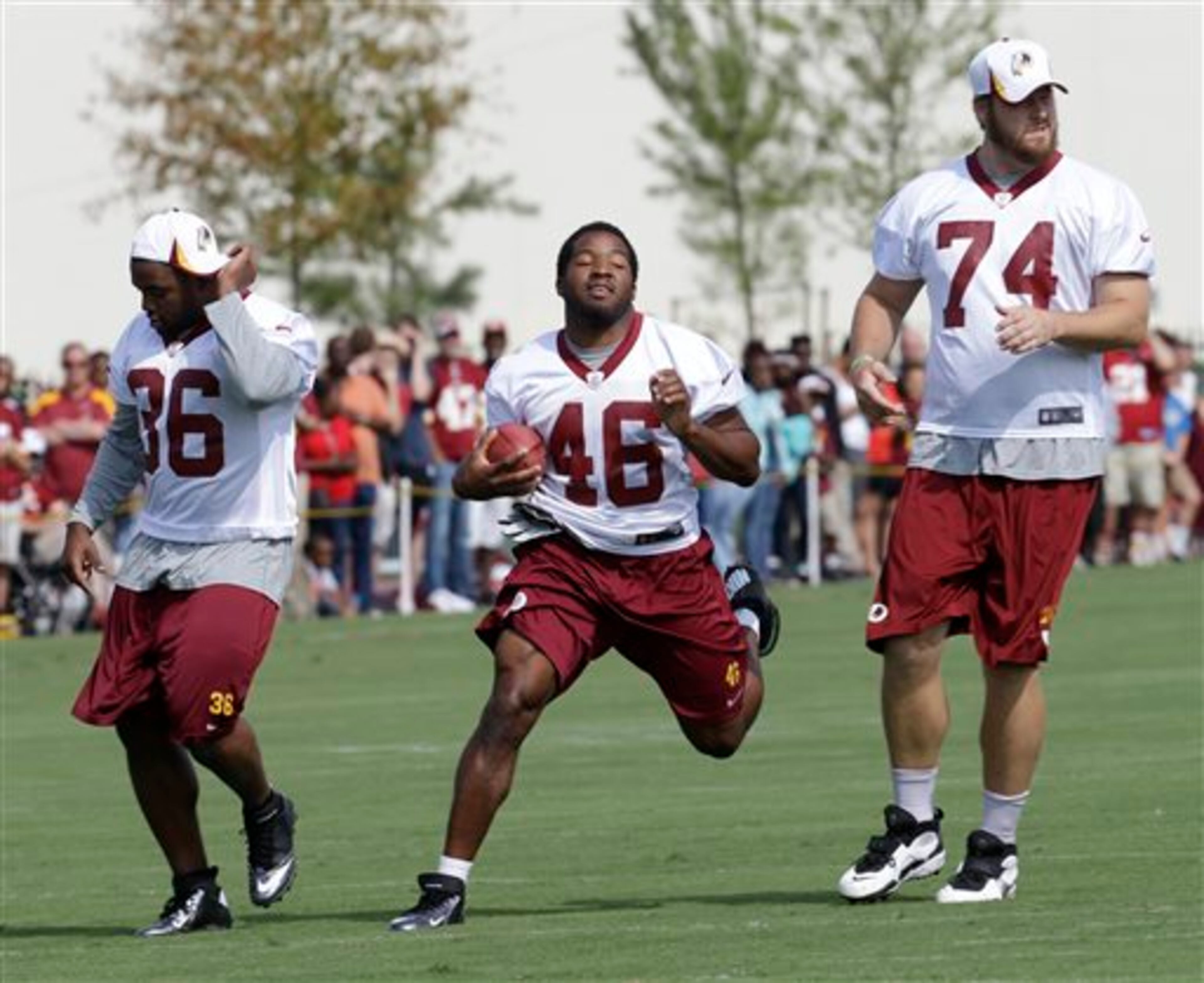Washington Redskins running back Alfred Morris (46) runs a play along with Darrel Young (36) and Tyler Polumbus (74) as the team begins their training camp at the NFL football teams new practice facility in Richmond, Va. Thursday, July 25, 2013. (AP Photo/Steve Helber)