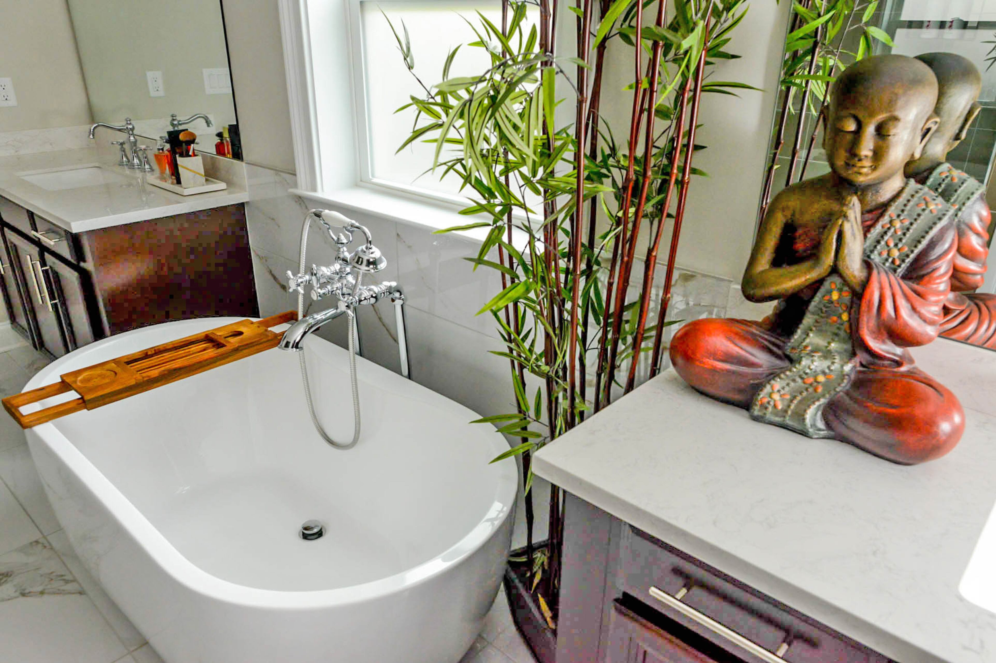 In the marble master bathroom, a Buddha statue from Pier1 Imports is positioned next to a freestanding tub as bamboo brings greenery into the space.