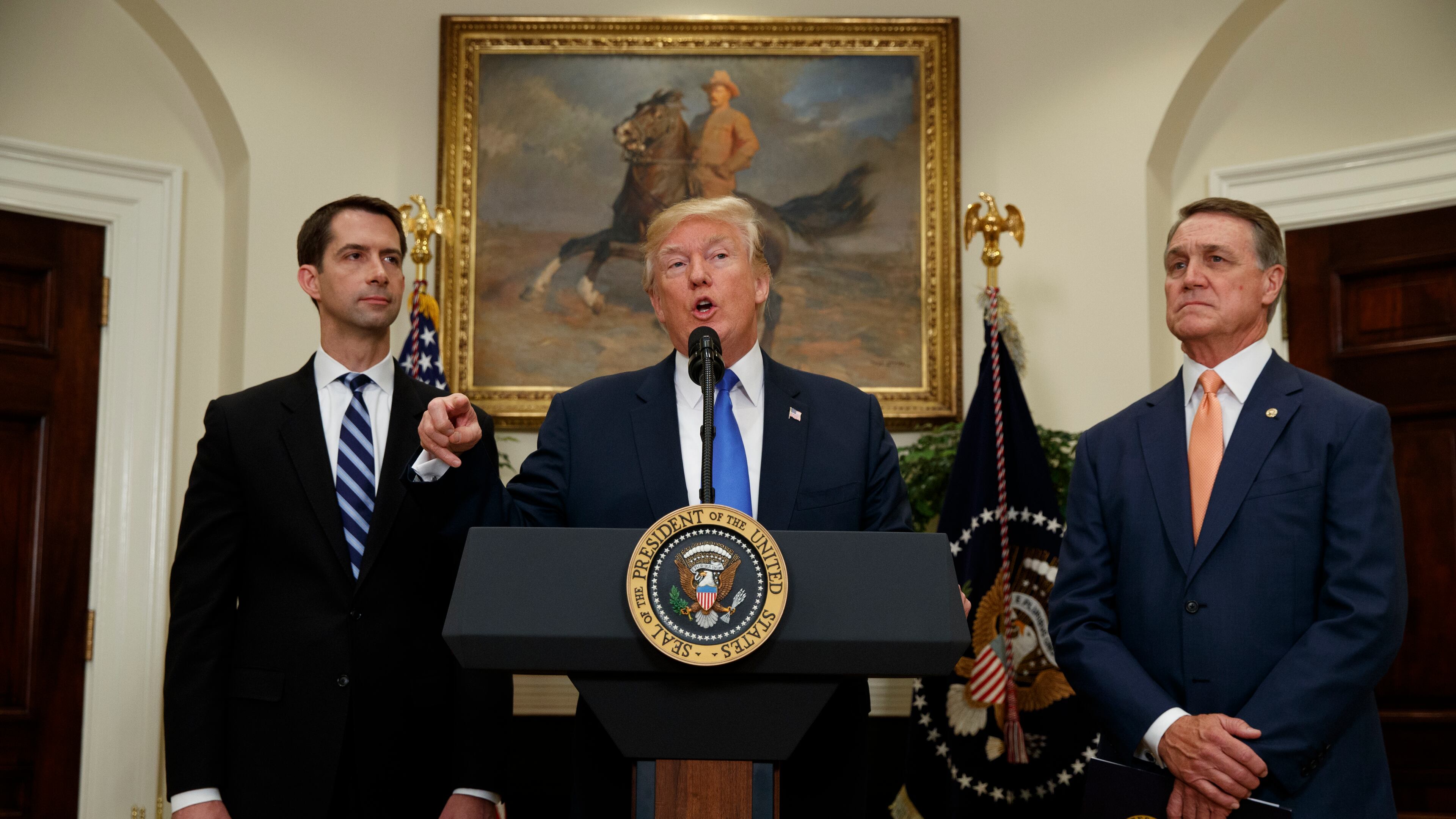 President Donald Trump, flanked by Sen. Tom Cotton, R- Ark., left, and Sen. David Perdue, R-Ga., speaks in the Roosevelt Room of the White House in Washington, Wednesday, Aug. 2, 2017. (AP Photo/Evan Vucci)