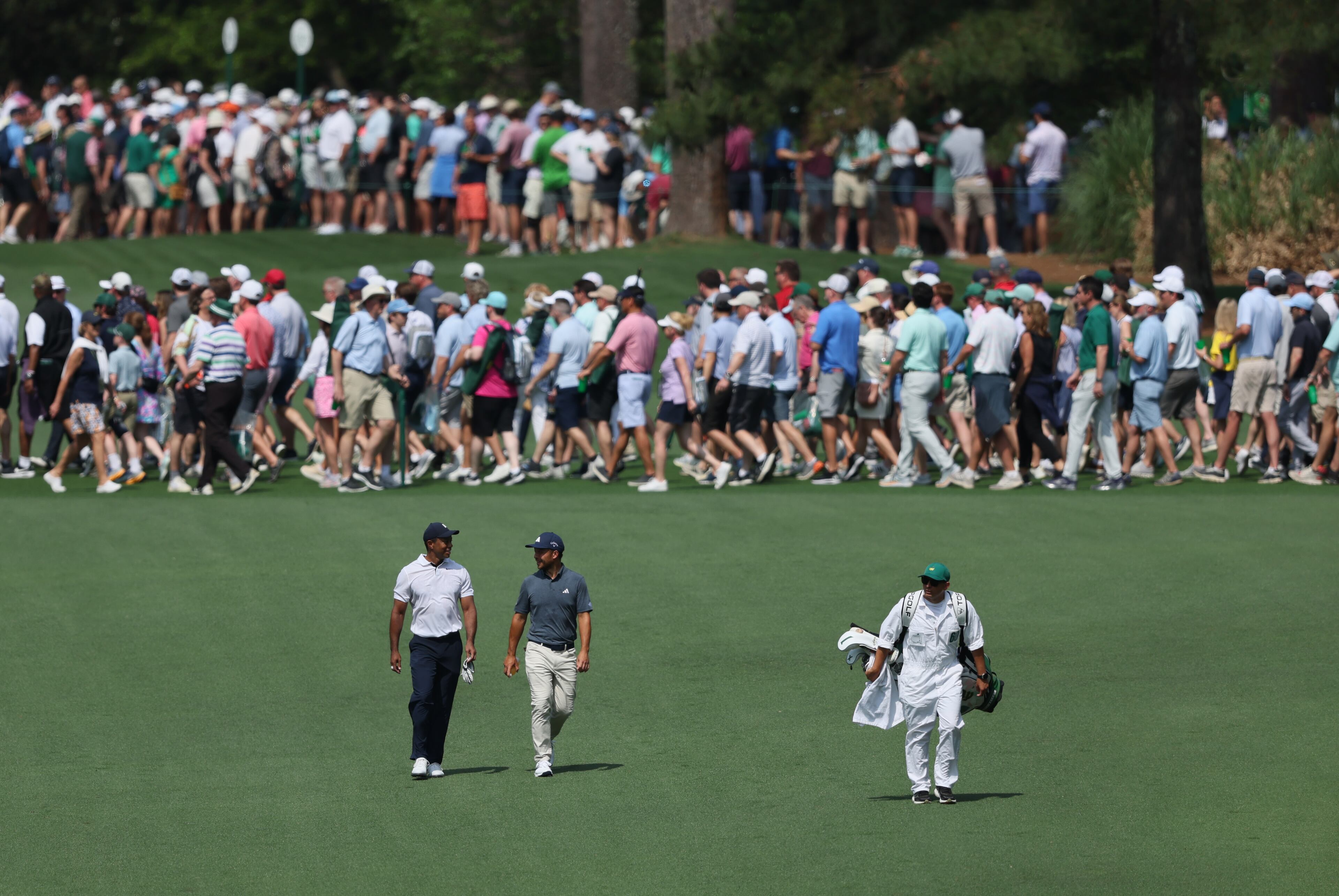 Tiger Woods and Xander Schauffele walk down fairway on seventh hole on the first round of the 2023 Masters Tournament at Augusta National Golf Club, Thursday, April 6, 2023, in Augusta, Ga. (Jason Getz / Jason.Getz@ajc.com)