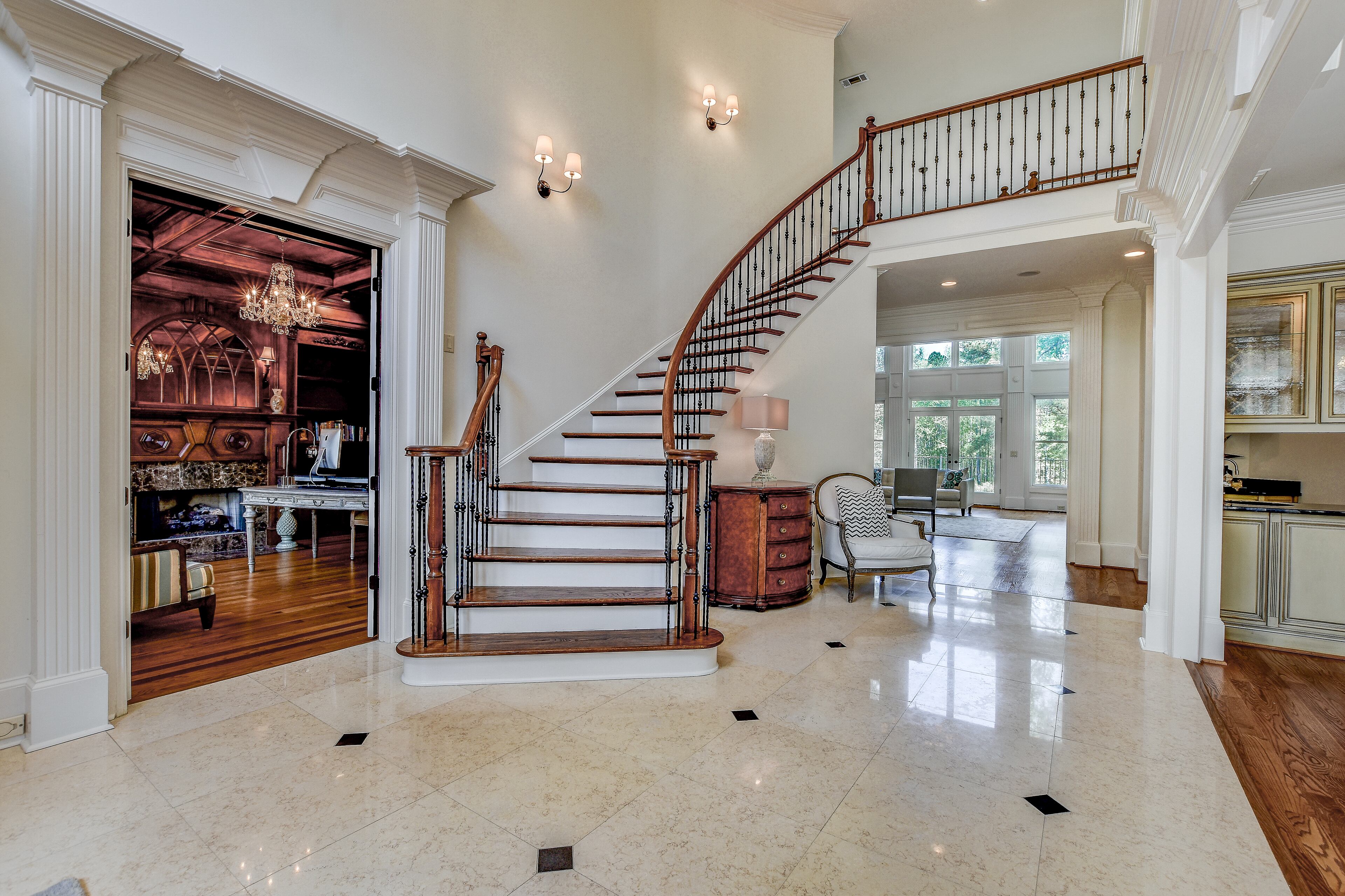 Beautiful spacious foyer featuring the grand curved staircase and glimpse into the office den. Text by Christela Becker