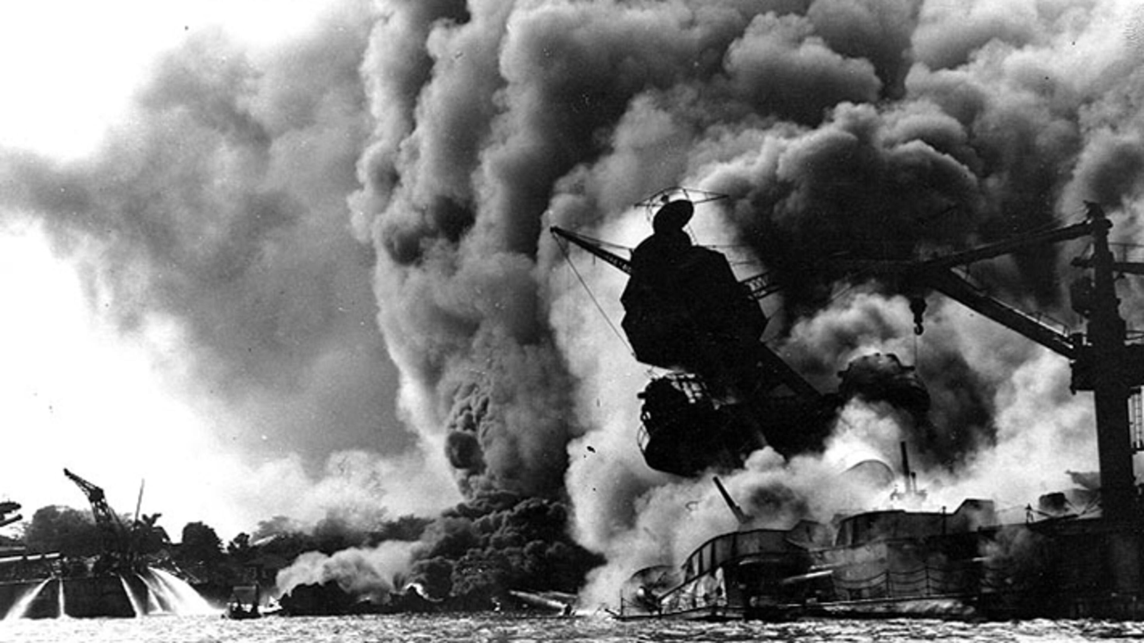The USS Arizona was bombed at Pearl Harbor on Dec. 7, 1941. At left, men on the stern of USS Tennessee are playing fire hoses on the water to force burning oil away from their ship.