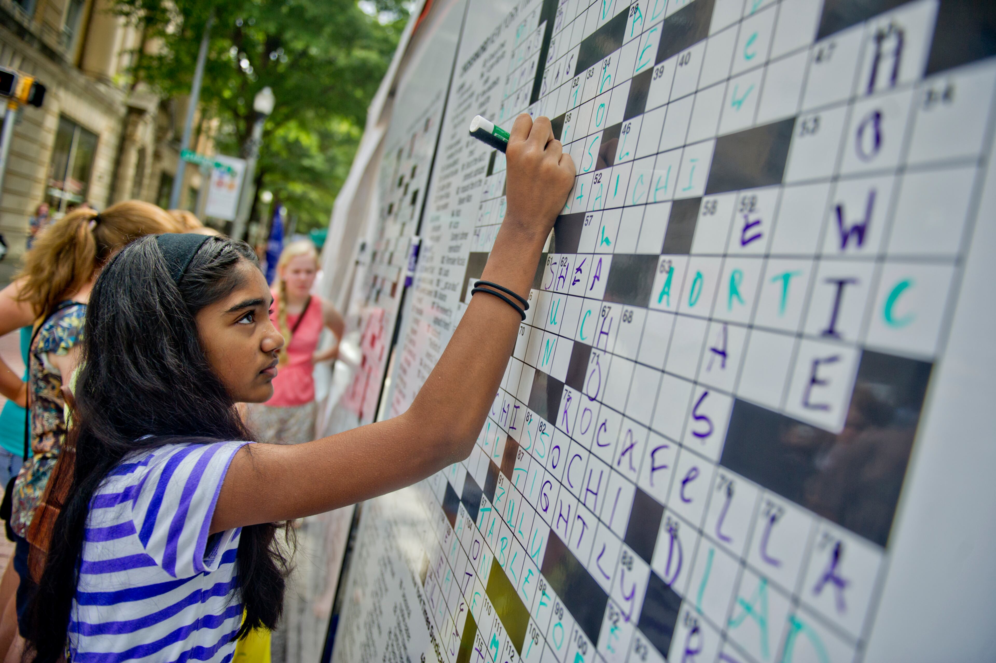 Smruthi Balasubramaniam (left) fills in the answer to a giant crossword puzzle during the AJC Decatur Book Festival on Saturday, August 30, 2014. The ninth annual event saw tens of thousands of people come out to the downtown Decatur area to meet with world-class authors, illustrators, editors, publishers, booksellers, and artists for a weekend filled with literature, music, food, art, and fun.