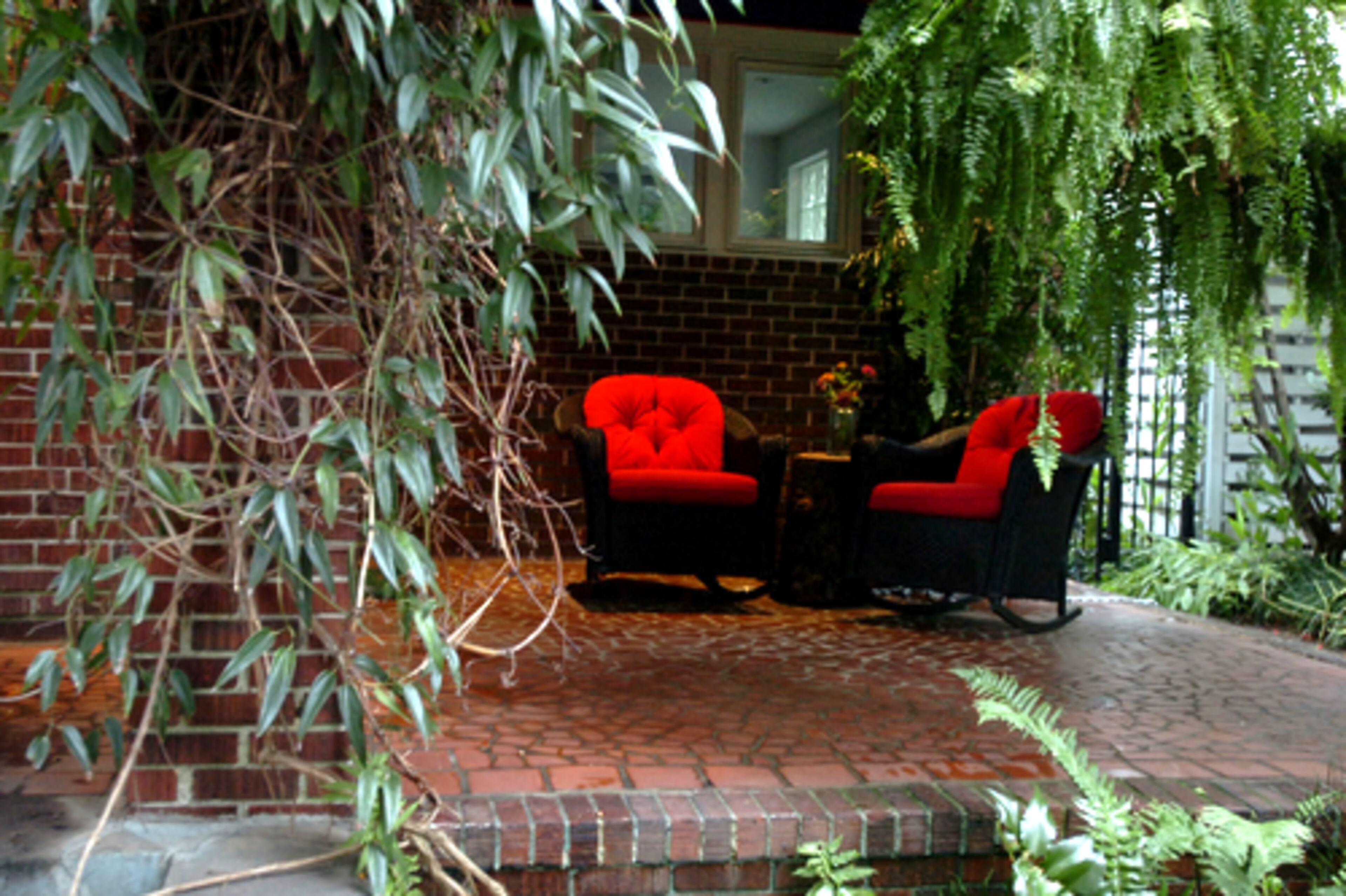 Interior designer Murray Vise uses a tree stump as a table on his Argonne Avenue porch, which is across the street from Dawn Landau. Other features of the porch include two Lloyd Loom rockers and a bamboo palm.