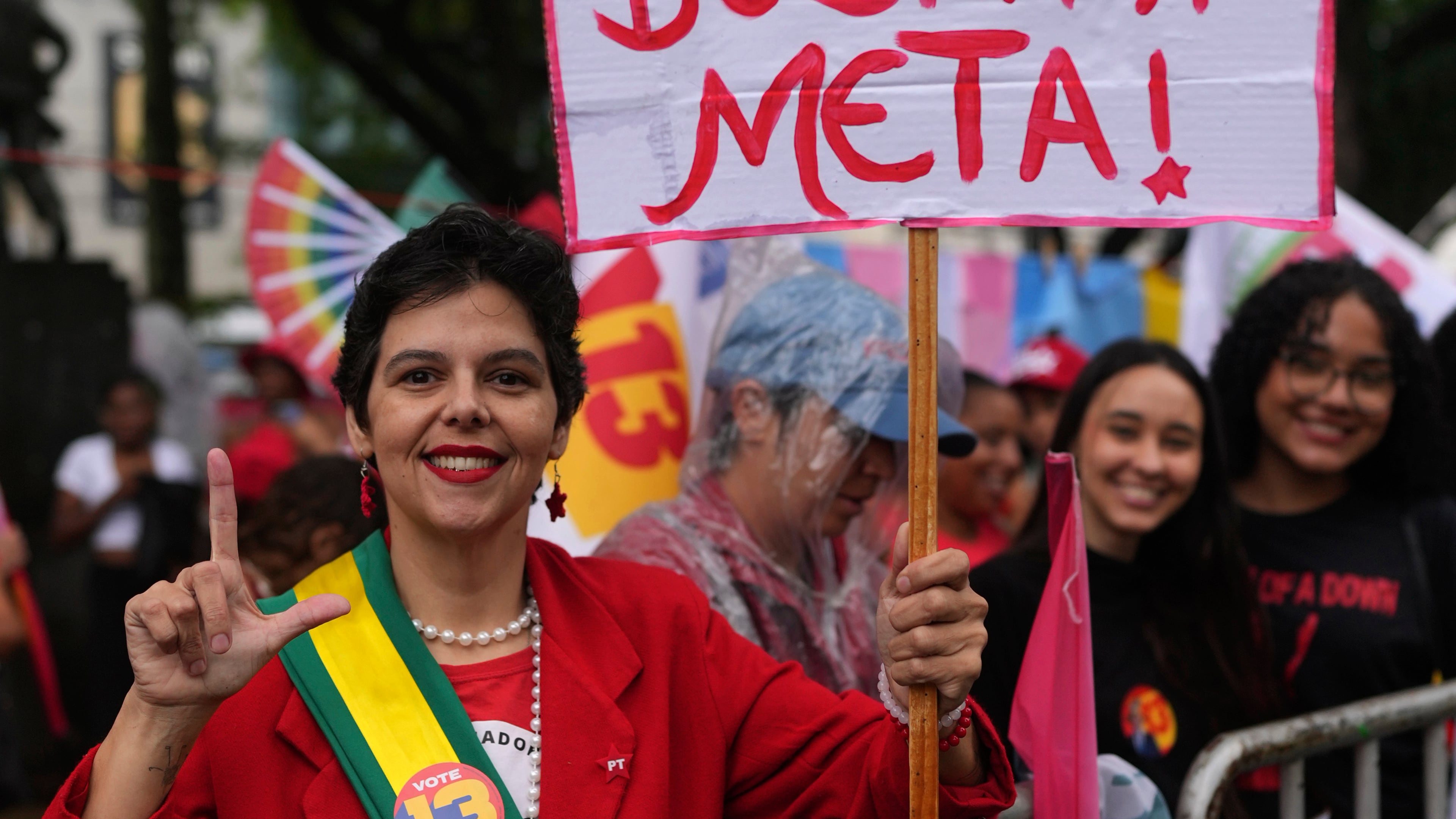A supporter holds a sign with a message reading in Portuguese, "When we reach the goal, we double the goal," referring to Meta Platforms and concerns about possible election interference, before the arrival of Brazilian President Luiz Inacio Lula da Silva, who is running for reelection, at a campaign rally in Juiz de Fora, Minas Gerais state, Brazil, Friday, Oct. 16, 2026. (AP Photo/Silvia Izquierdo)