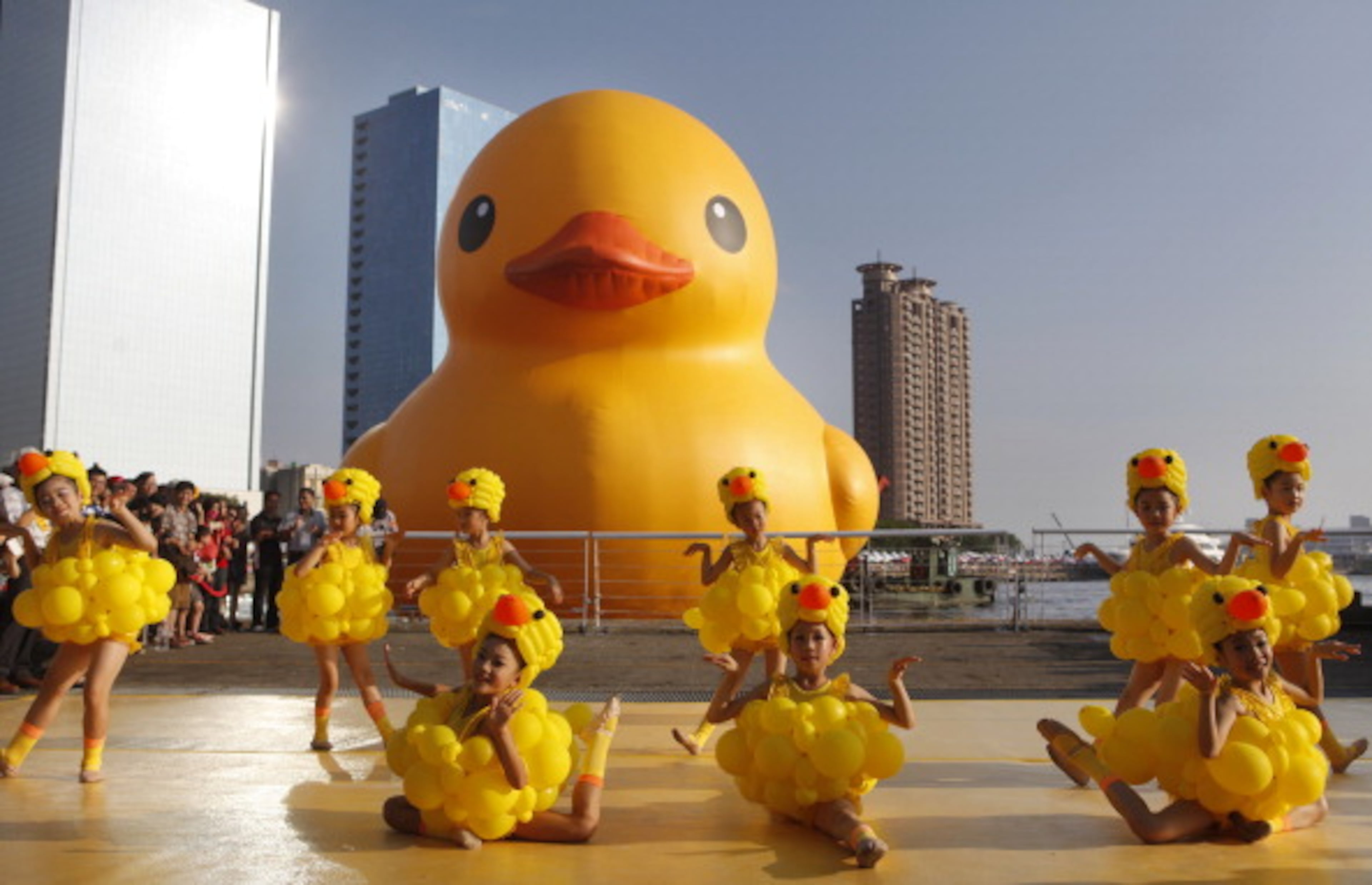 KAOHSIUNG, TAIWAN - SEPTEMBER 19: Girls dress as ducks as people gather to see a giant Rubber Duck by Dutch conceptual artist Florentijin Hofman at Glory Pier on September 19, 2013 in Kaohsiung, Taiwan. The 'Rubber' Duck,' is traveling the world and will stop in Kaohsiung from September 19 to October 20. (Photo by Ashley Pon/Getty Images)