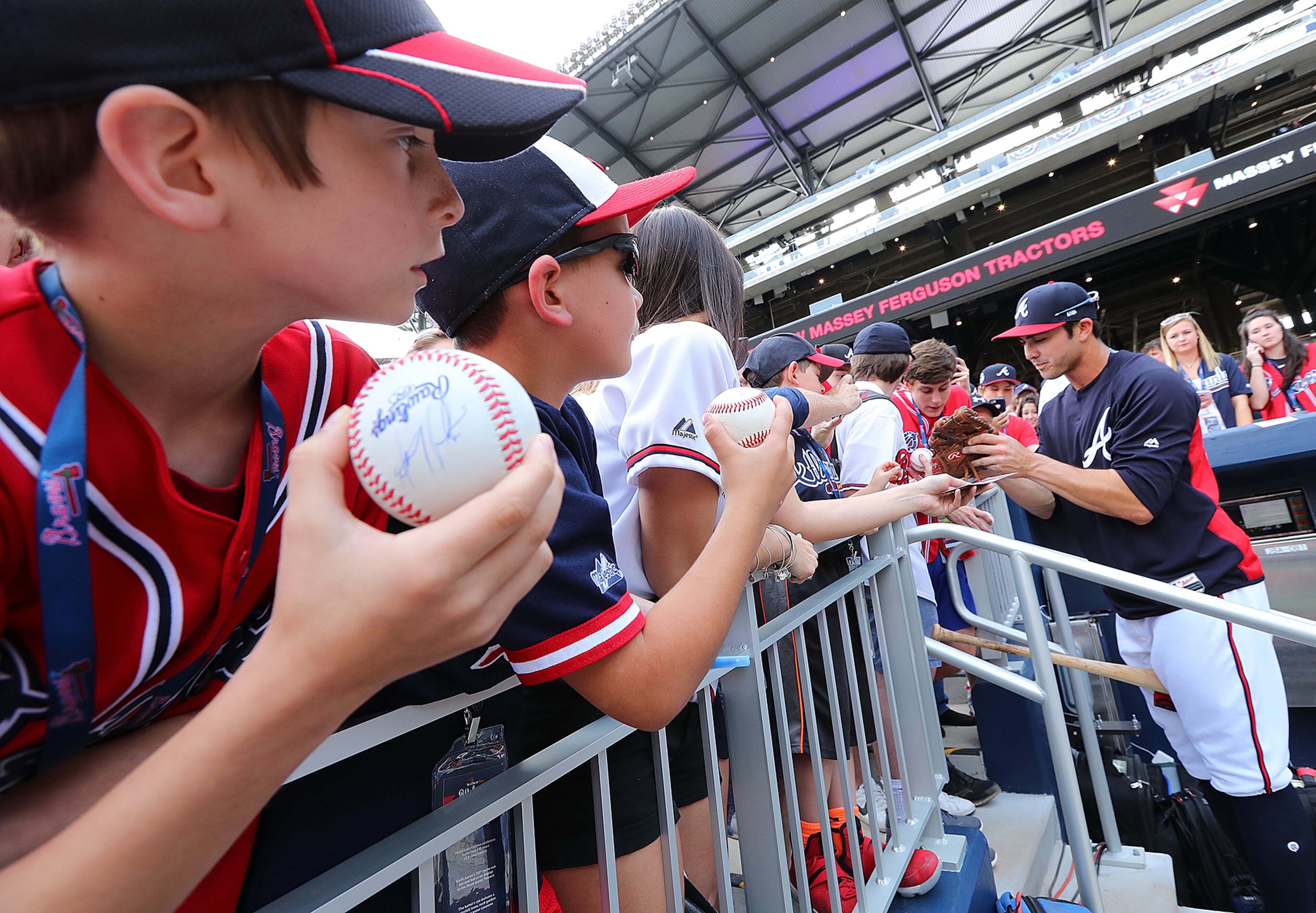 Chase d'Arnaud signs autographs for fans at the dugout during the Braves home opener against the Padres in the new stadium at SunTrust Park Friday.