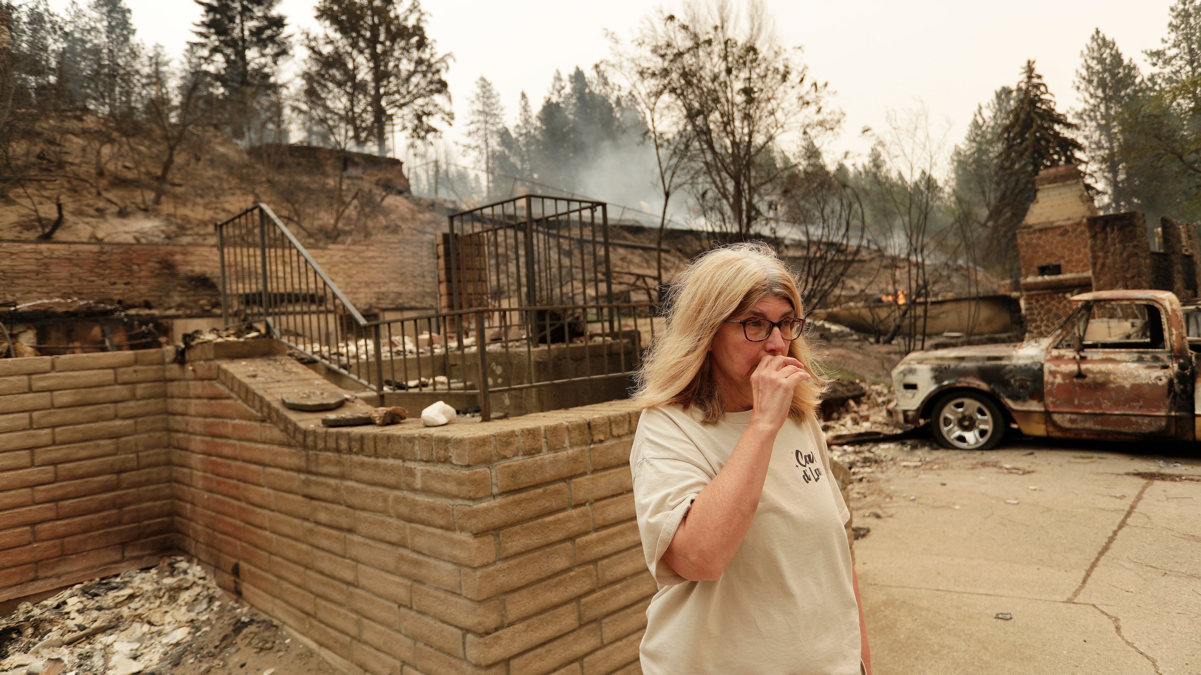 Kimberley Sather stands at the duplex she rents on W. Indian Trail Rd. after it burned in a wildfire in Spokane, Wash., Sunday, Aug. 2, 2026. (AP Photo/Young Kwak)