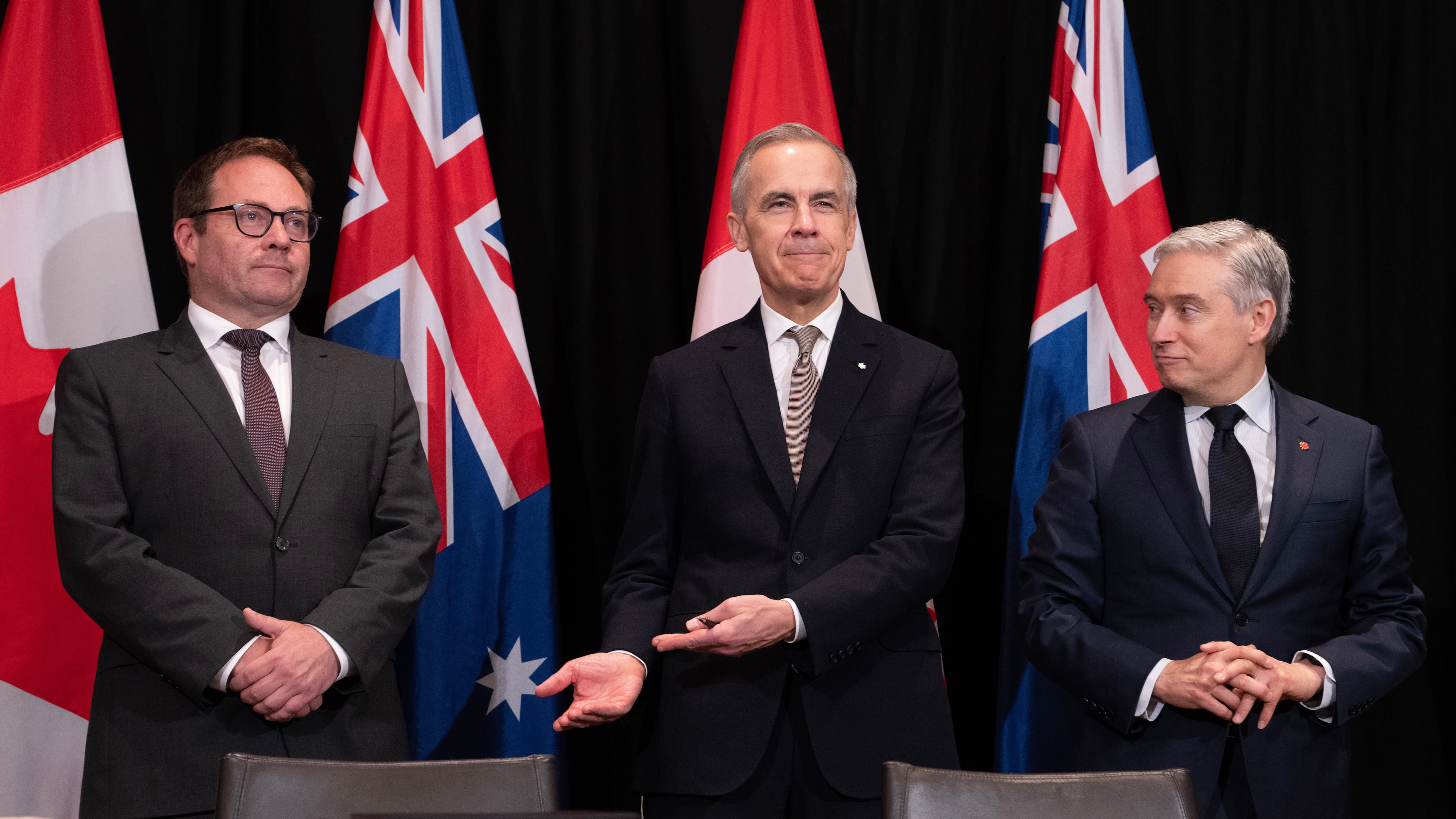 Canada's Prime Minister Mark Carney, center, gestures to Daniel Mulino, Australian Assistant Treasurer as he is introduced at the start of a signing ceremony, as Canada's Finance and National Revenue Minister Francois-Philippe Champagne, right, looks on, in Sydney, Australia, Wednesday, March 4, 2026. (Adrian Wyld/The Canadian Press via AP)