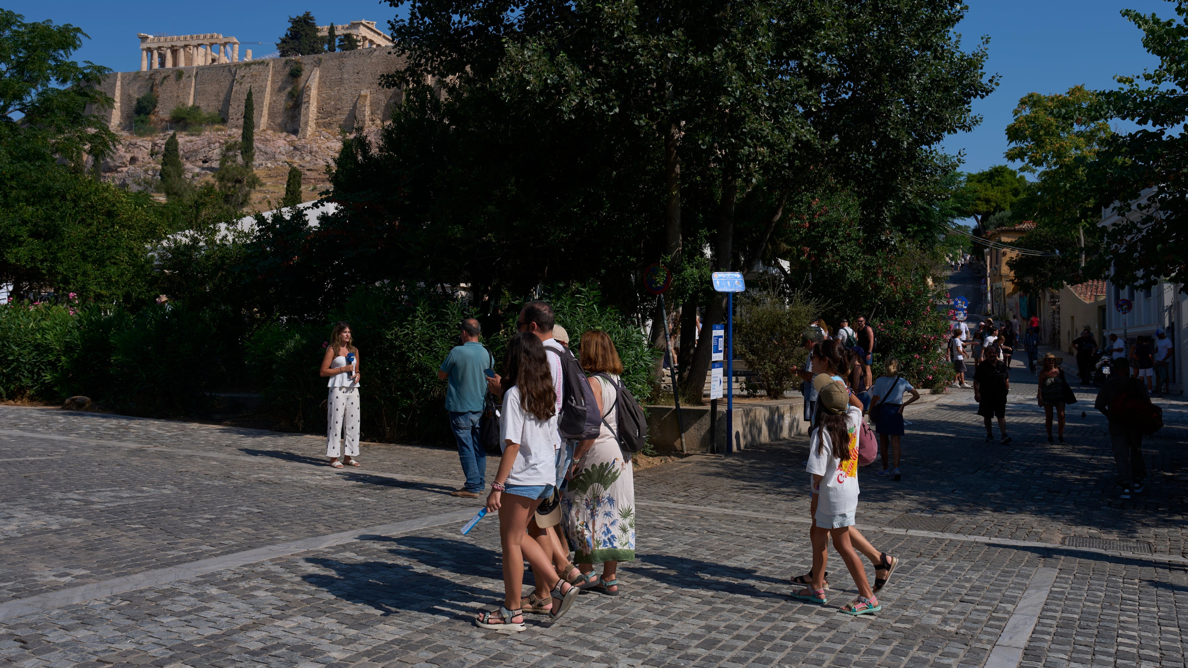 Tourists walk near the Acropolis in Athens, Greece, Tuesday, July 21, 2026, after two tourists were stabbed and injured nearby in an attack on a pedestrian street near the entrance to the archaeological site. (AP Photo/Petros Giannakouris)