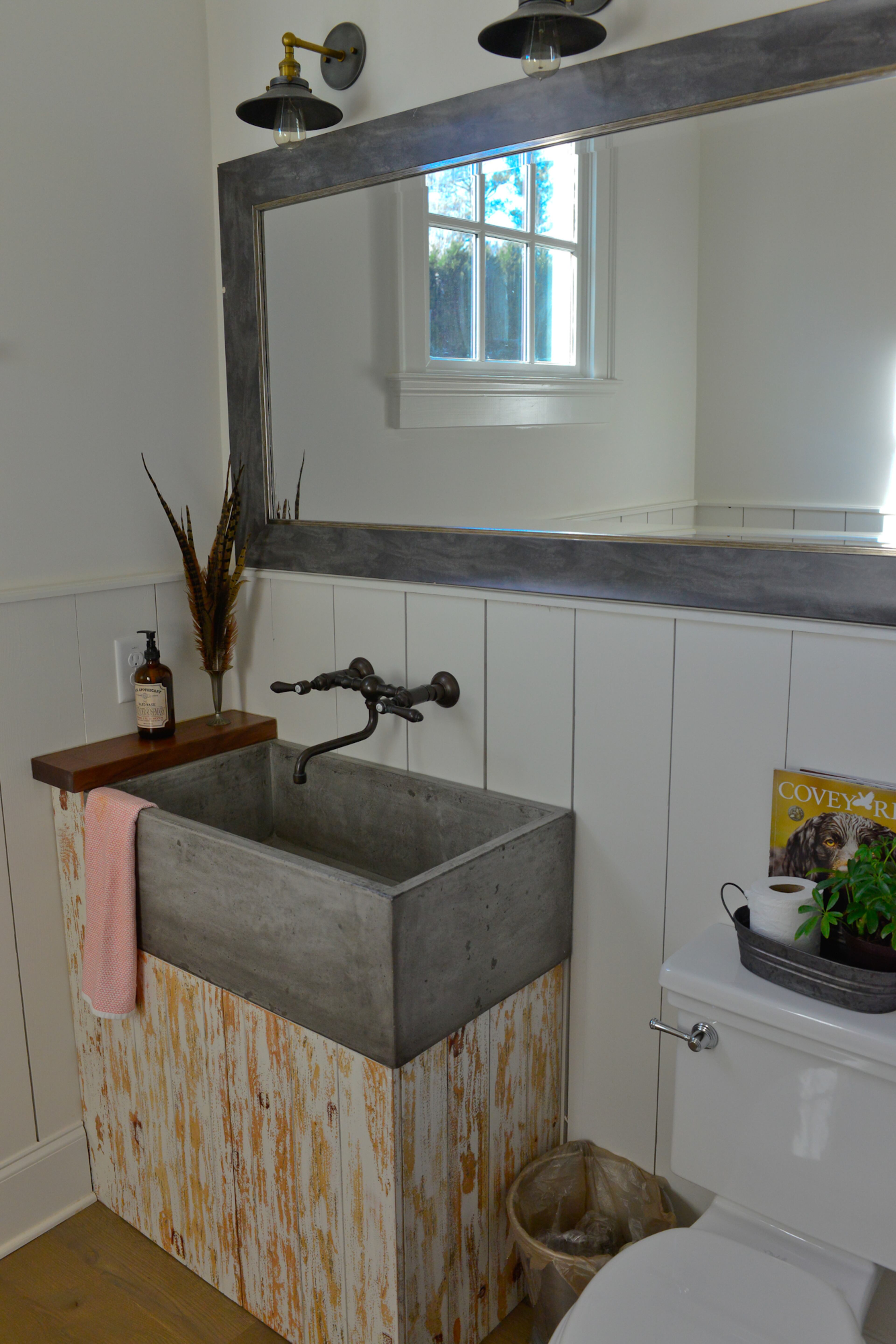 A farmhouse concrete sink sits atop a custom-made wood vanity in a guest bathroom. Copper faucets that will antique over time and light fixtures from RH enhance the room's rustic character. Text by Lori Johnston and Keith Still/Fast Copy News Service.