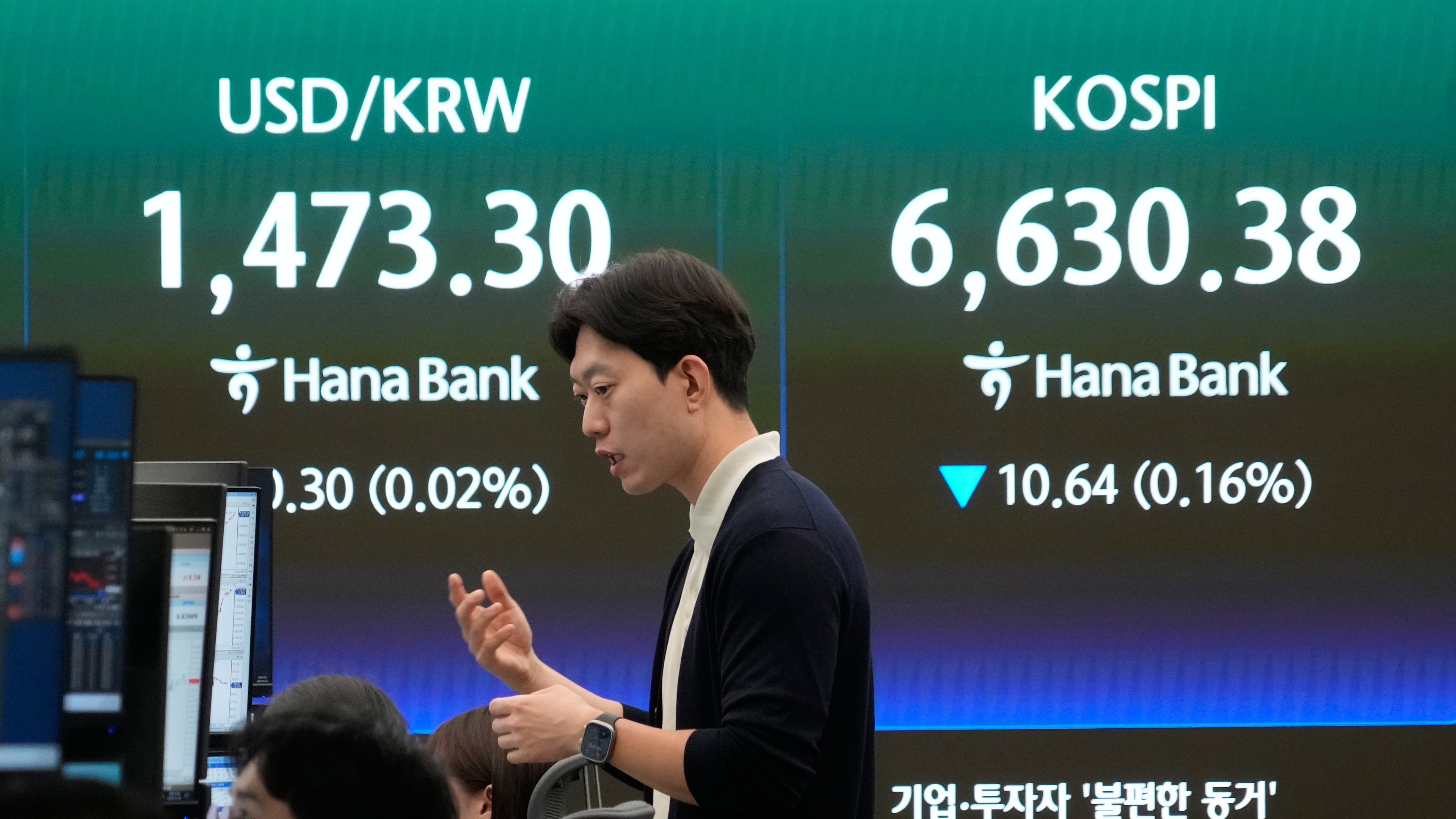 A currency trader reacts near a screen showing the Korea Composite Stock Price Index (KOSPI), right, and the foreign exchange rate between U.S. dollar and South Korean won at the foreign exchange dealing room of the Hana Bank headquarters in Seoul, South Korea, Wednesday, April 29, 2026. (AP Photo/Ahn Young-joon)