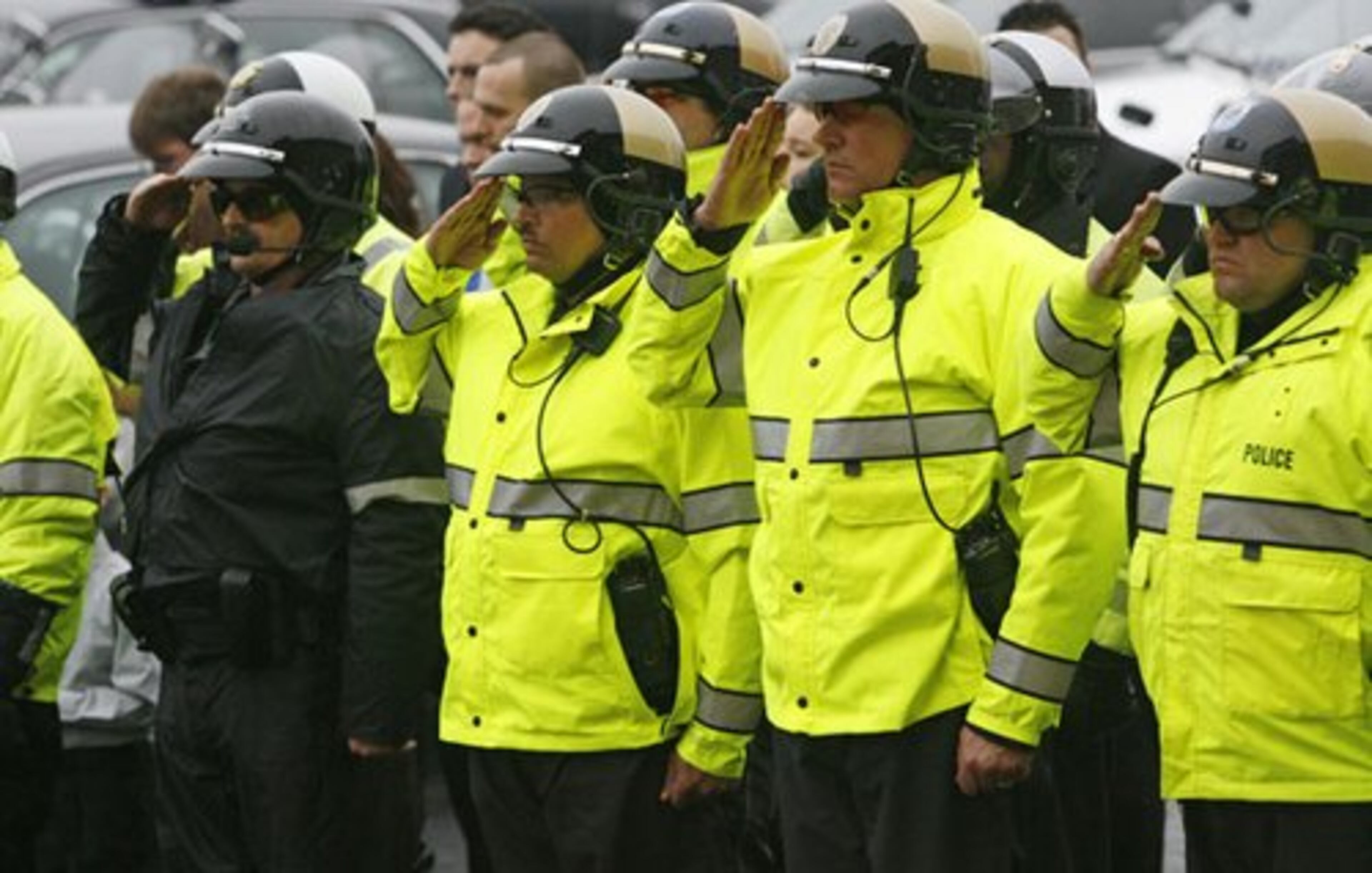 Motorcycle patrol officers who led the motorcade to the church salute as Norman's casket is carried into the church for the funeral.