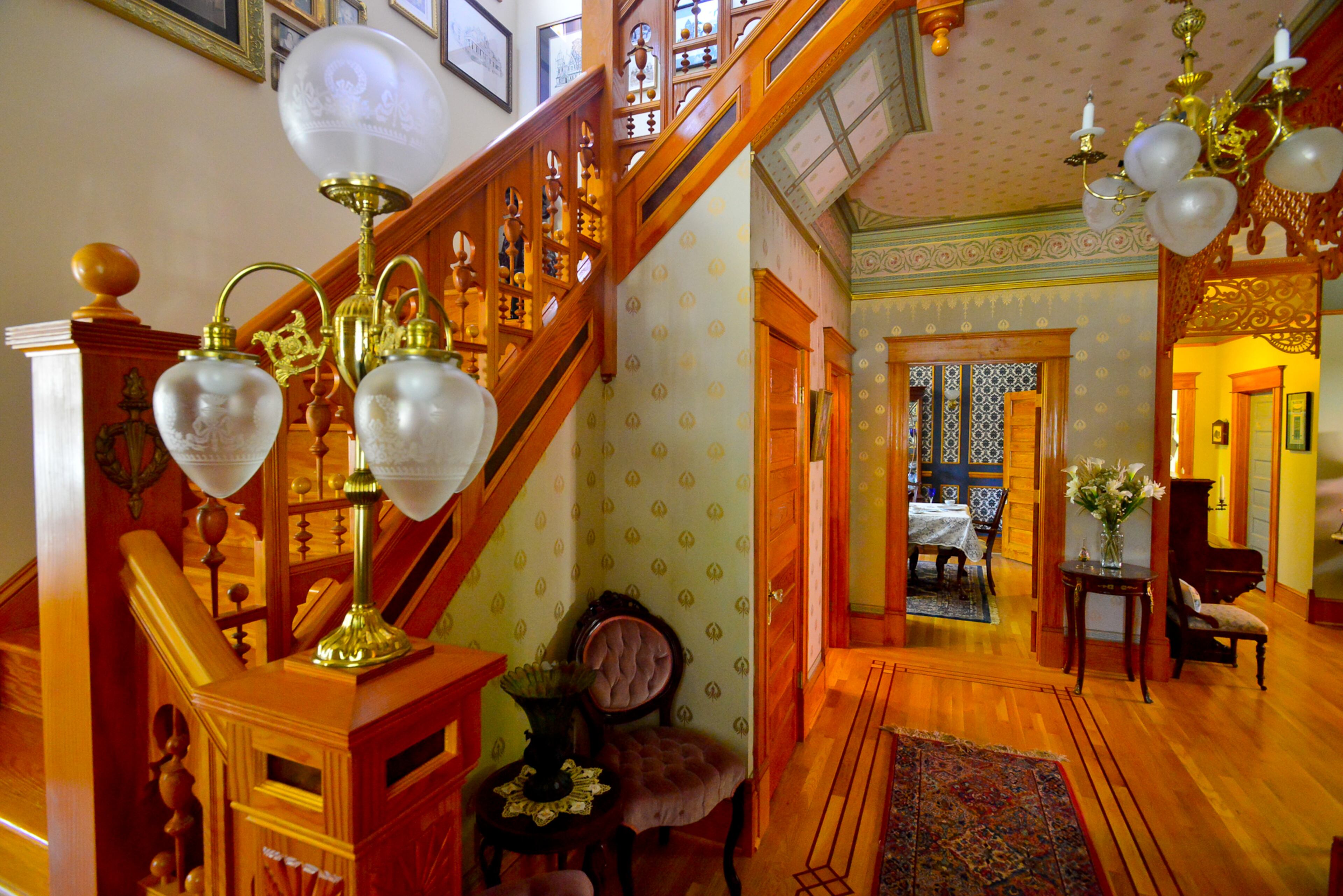 The first floor of the Grant Park home has ornate Queen Anne-style interiors including various patterns of wallpaper selected by homeowners Mike and Carolyn Dufano and a staircase inspired by a visit to the W.H. Stark House in Orange, Texas.