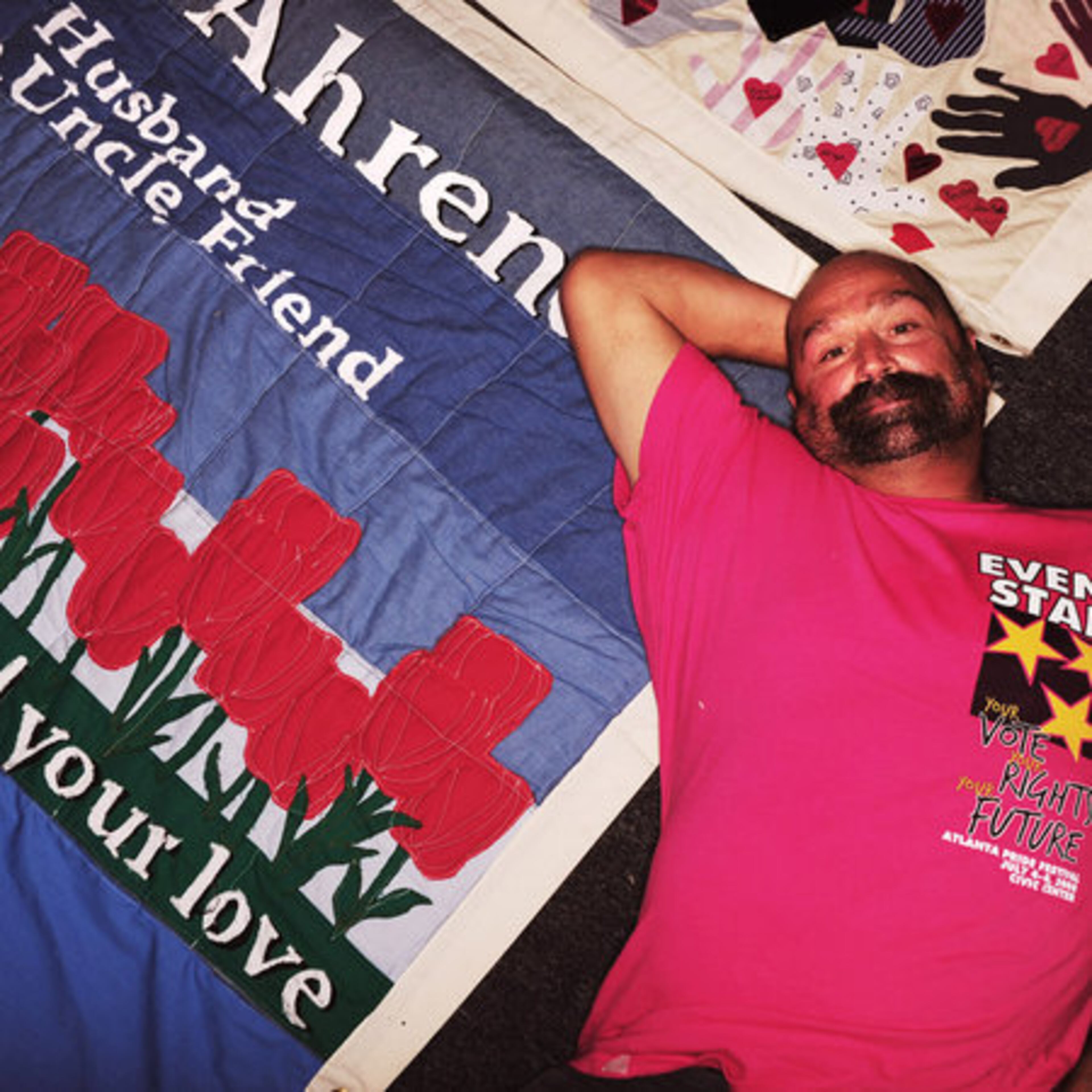 Al Pellenberg, a 23-year volunteer with Pride, lies atop the AIDS quilt made in honor of his partner Max Lee Ahrendt, who passed away 20 years ago. Pellenberg was one of many who visited the quilt room to think about friends and partners now gone.