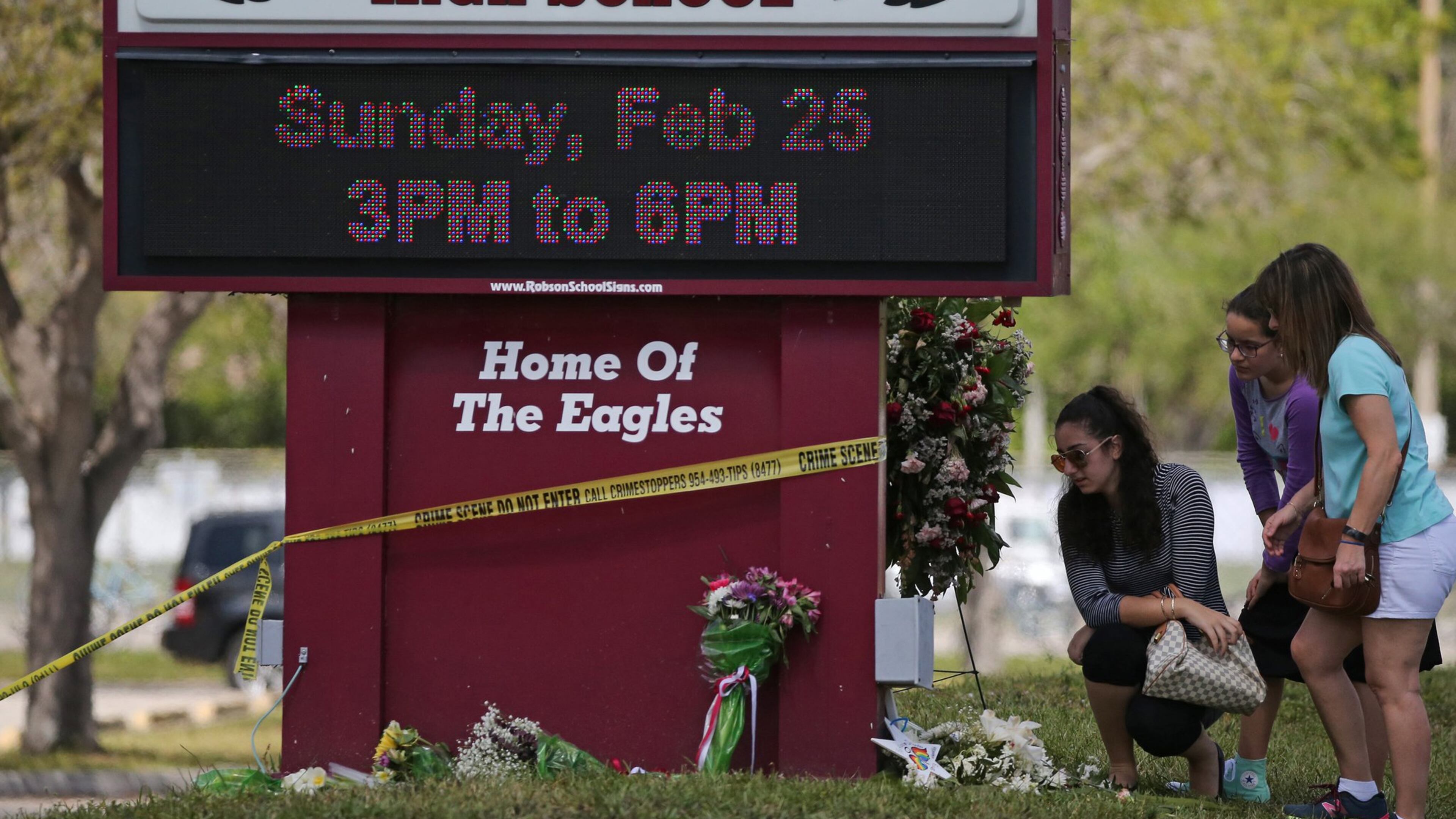 Mourners bring flowers as they pay tribute at a memorial for the victims of the shooting at Marjory Stoneman Douglas High School during an open house as parents and students returned to the school for the first time since 17 people were killed in a mass shooting at the school. (David Santiago/Miami Herald/TNS)