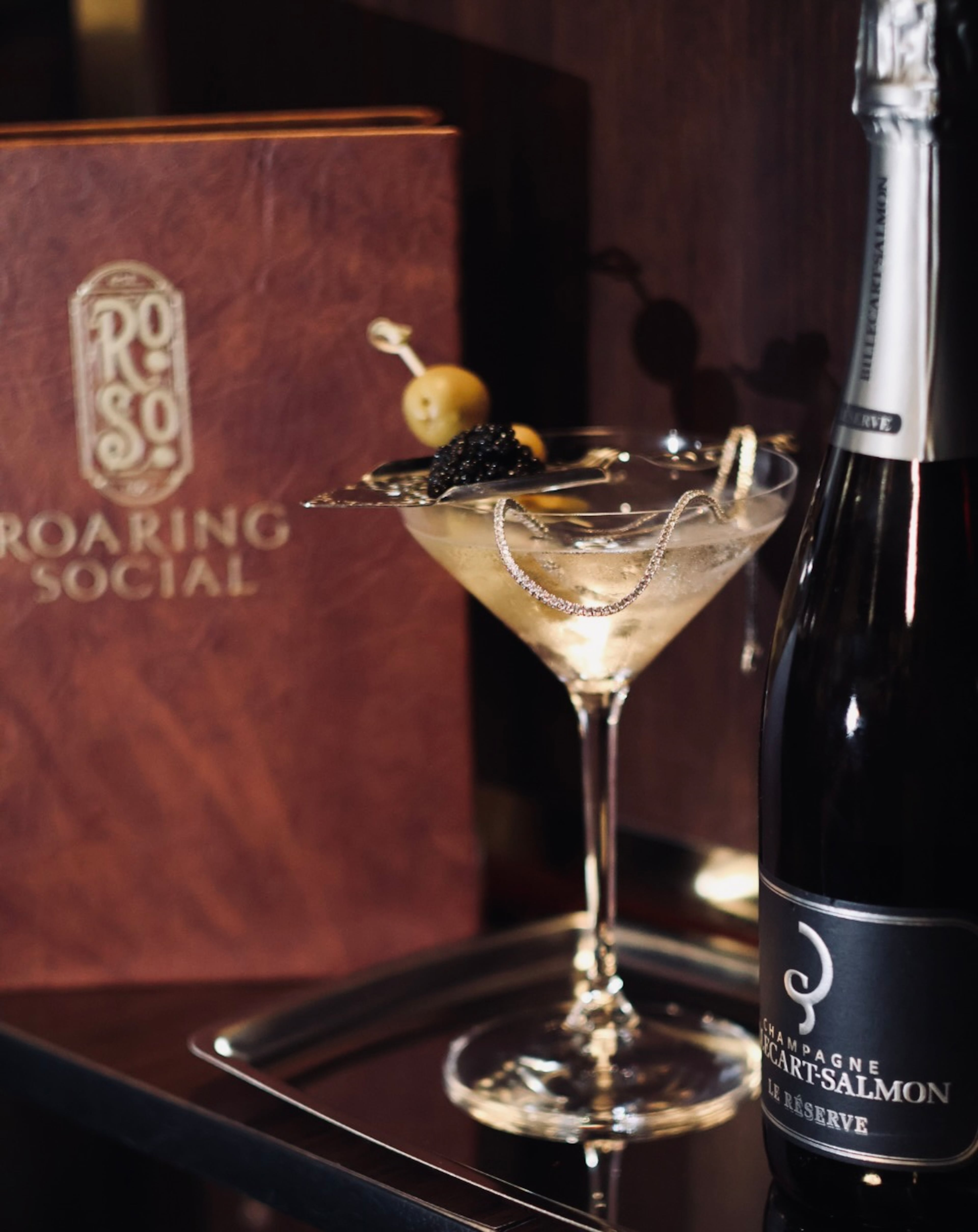 The roaring jewel martini is made with Beluga Gold Line Vodka and a dry vermouth rinse, then topped with Billecart-Salmon Champagne Le Reserve and garnished with olives and a spoonful of beluga caviar. (Courtesy of Solomon Brothers & Roaring Social)