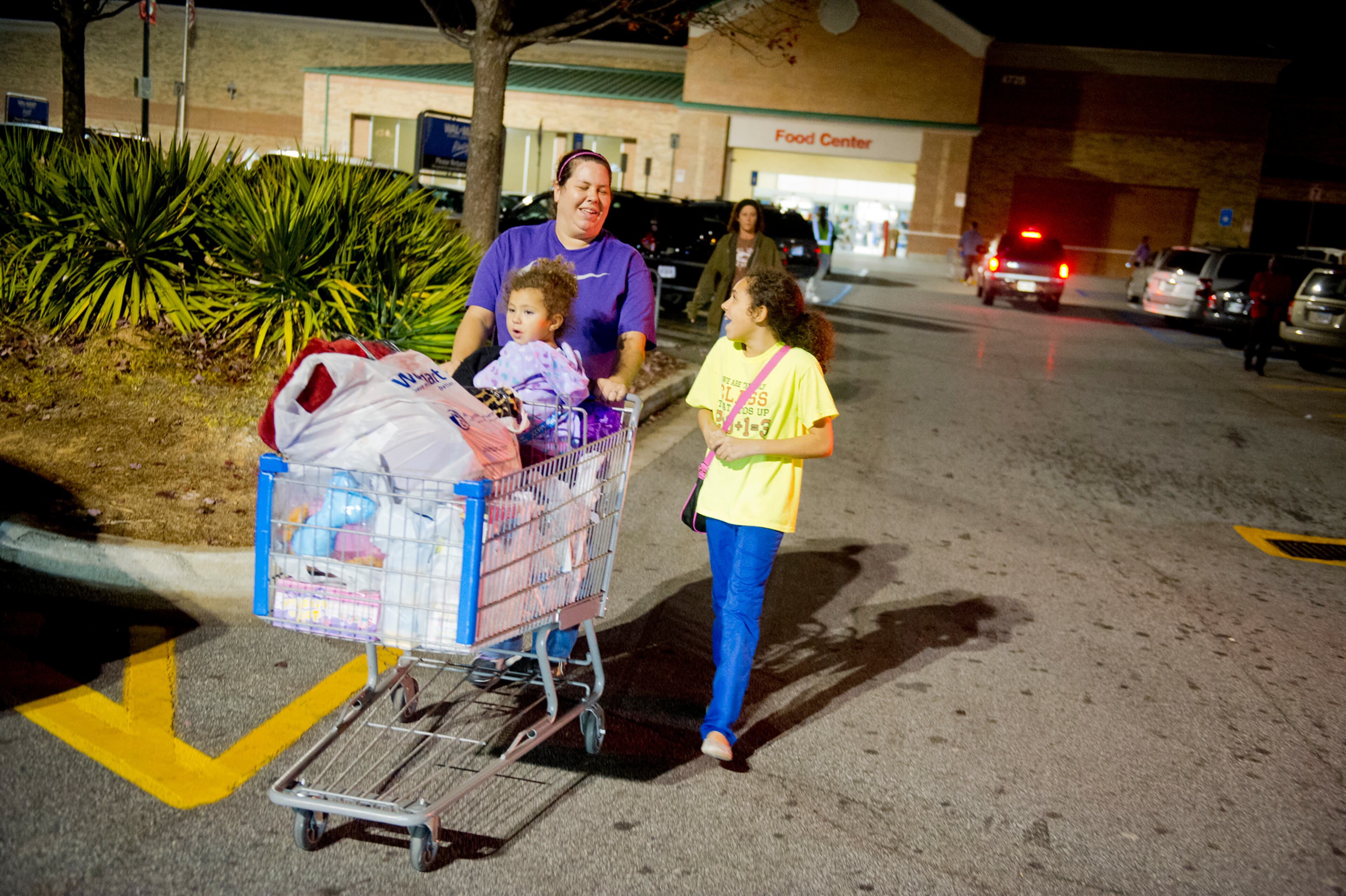 Briana Belfour (right) talks to her mother Priscilla as she pushes her sister Maghan in a shopping cart as they leave the Walmart near Perimeter Mall on Thursday, Nov. 22, 2012. Walmart and stores all over the metro early opened early for Black Friday.