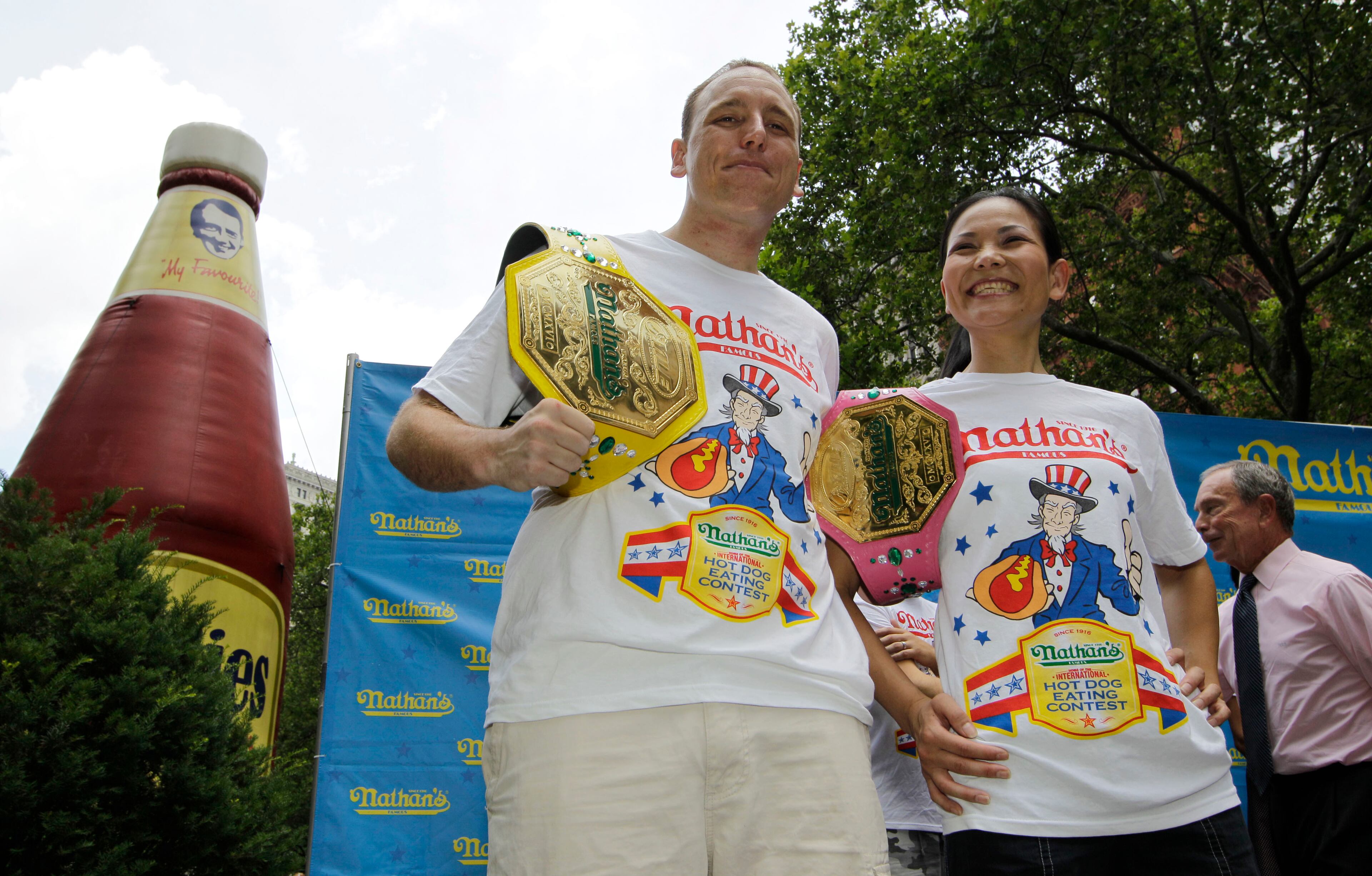 Five-time hot dog-eating world champion Joey Chestnut, left, and women's record-holder Sonya "The Black Widow" Thomas, pose for photographers following a weigh-in for contestants in the annual Coney Island Fourth of July international hot dog-eating contest in New York, Tuesday, July 3, 2012, at City Hall Park in New York. The event will take place midday Wednesday, July 4, in Coney Island, Brooklyn. Chestnut will try to break his own world record of downing 68 hot dogs and buns in 10 minute, while Thomas will headline the women's competition, facing 14 female eaters from the U.S. and Canada. New York Mayor Michael Bloomberg walks behind the pair, far right. (AP Photo/Kathy Willens)