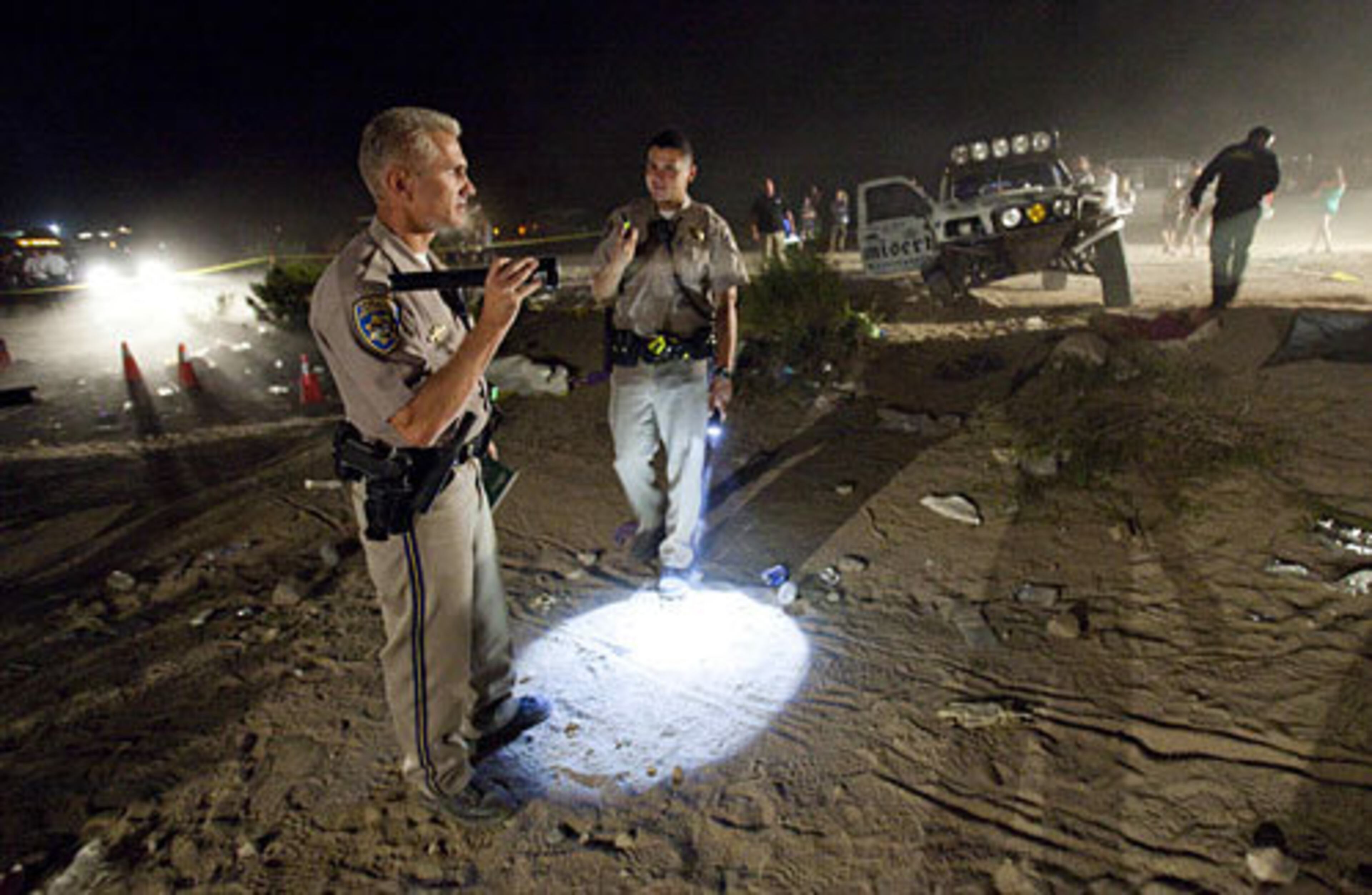California Highway Patrol officers examine the accident scene early Sunday morning. The CHP does not normally investigate crashes at organized events, but took the lead on this probe because of its scope. The federal Bureau of Land Management says the organizer of the off-road race in the California desert where eight people were killed was responsible for the safety of spectators at the event.