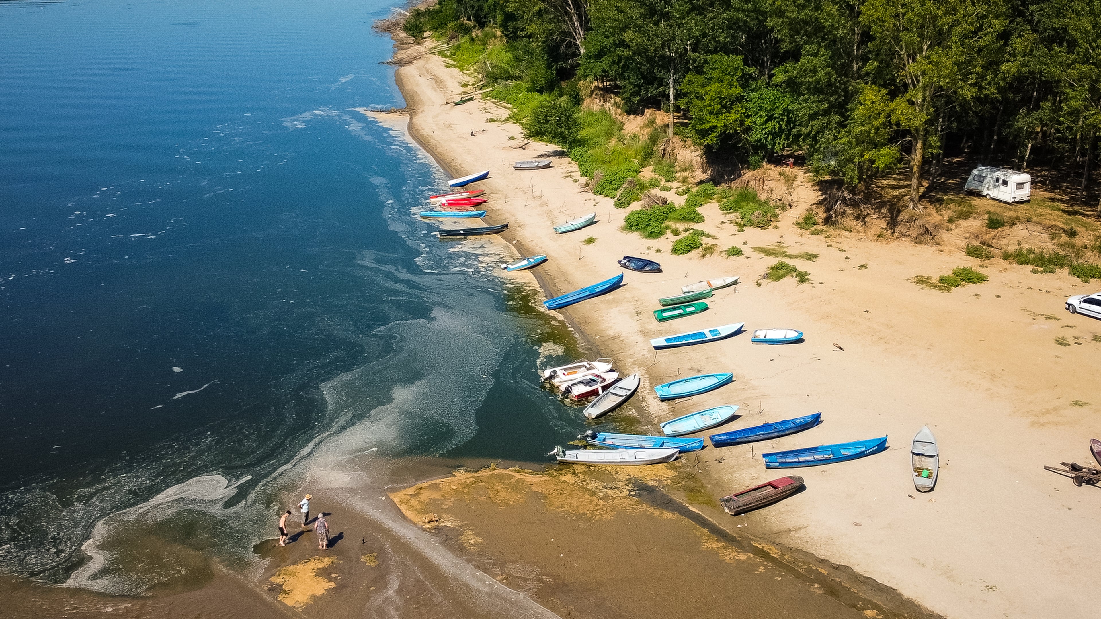 People stand on a bank of sand on the Danube River as usually submerged areas are exposed due to extreme low levels of the water following an extended period of drought in Corabia, Romania, Wednesday, July 29, 2026. (AP Photo/Nicolae Dumitrache)