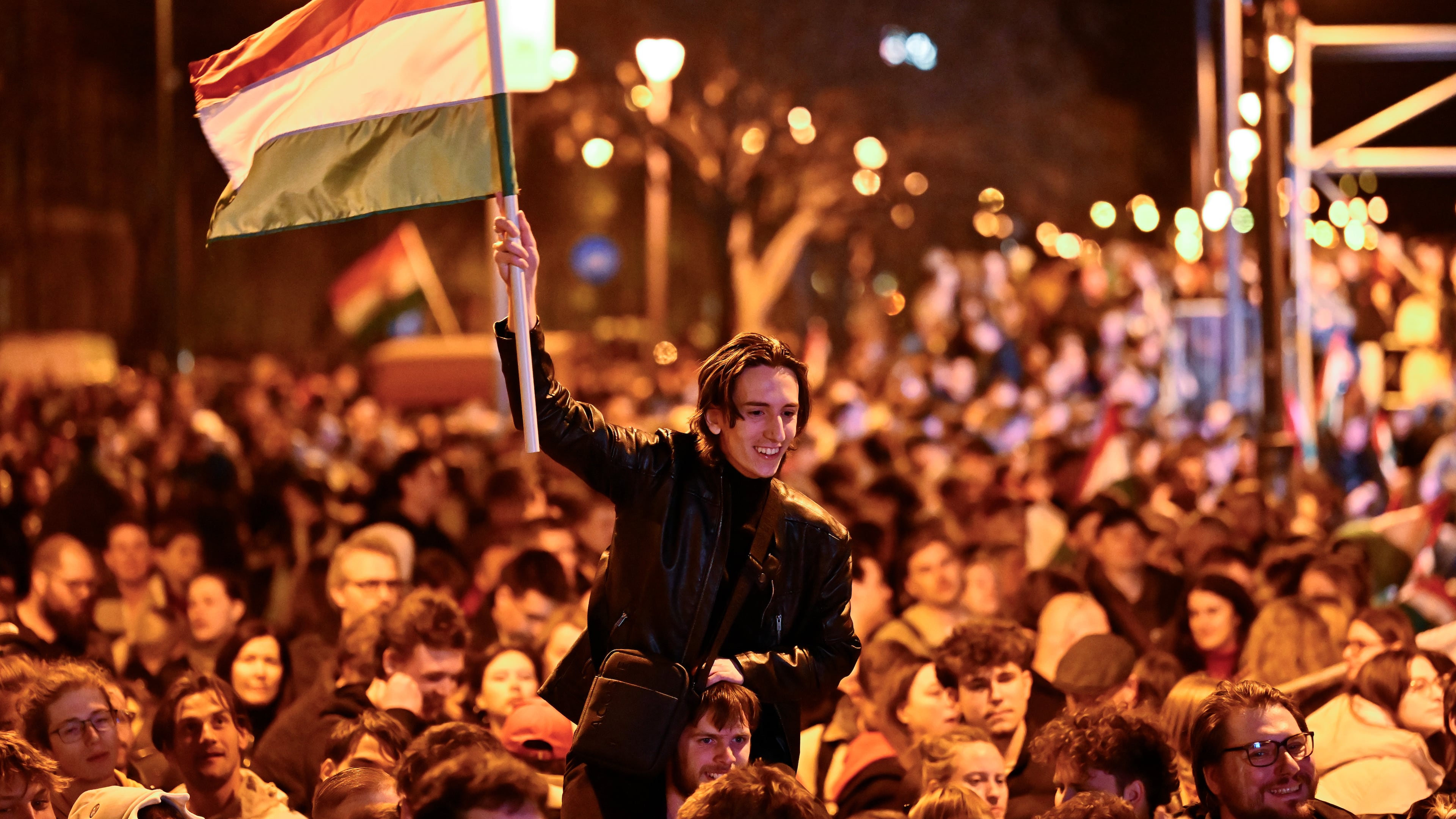 A man waves a Hungarian flag as he celebrates in the streets after the announcement of partial results of the Hungarian parliamentary in Budapest, Hungary, Sunday, April 12, 2026. (AP Photo/Denes Erdos)