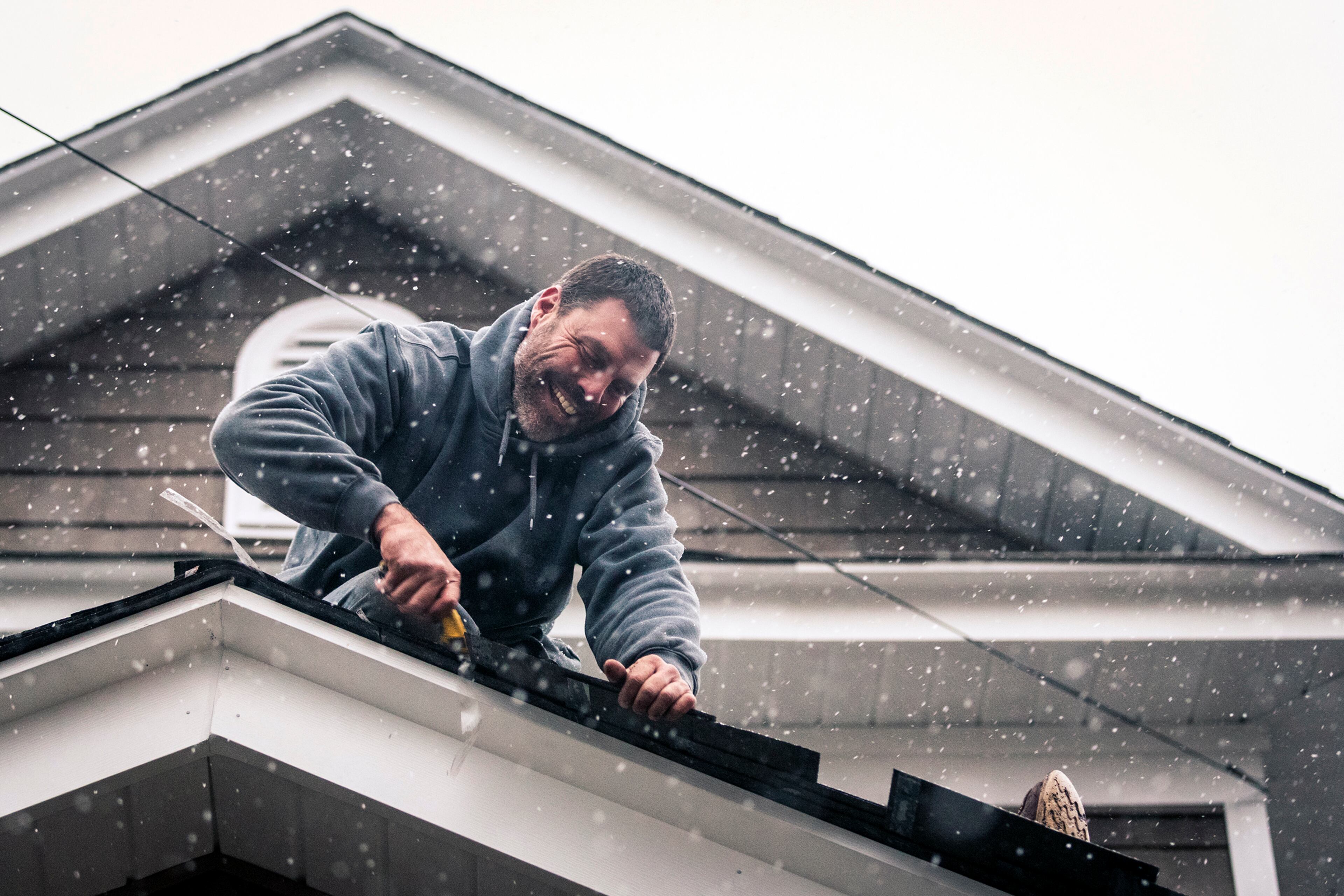 Travis Pfaff, owner of Pfaff Roofing, finishes up a roofing job on Spruce Street as snow begins to fall on Friday, Jan. 6, 2016 in Winston-Salem, N.C. (Andrew Dye/The Winston-Salem Journal via AP)