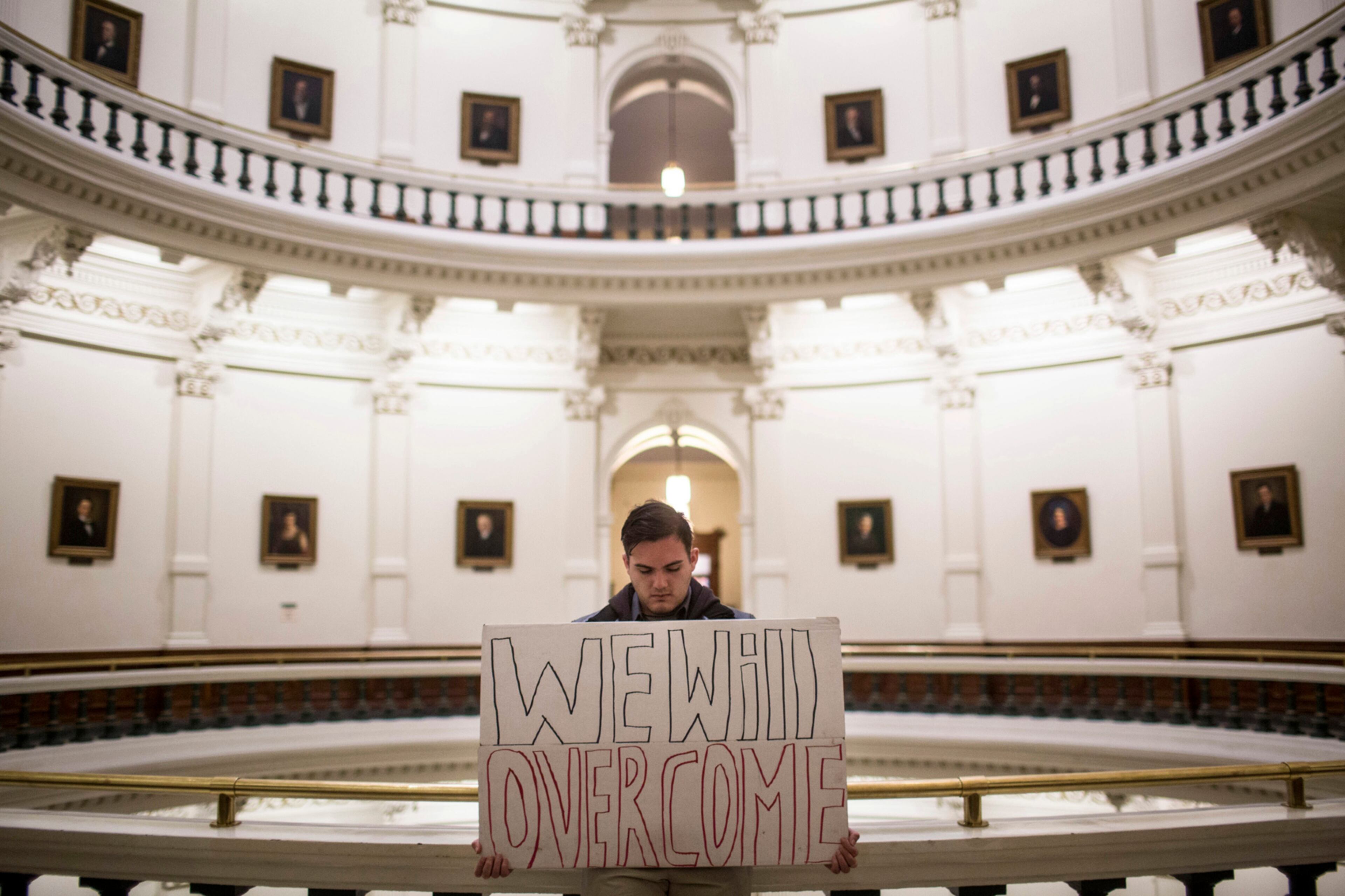 Jacob Rubio holds a sign that reads "We will overcome," in the rotunda of the state Capitol shortly after the Electoral College cast their vote in Austin, Texas, Monday, Dec. 19, 2016. The ballots of three dozen Texas presidential electors Monday put Donald Trump over the 270 electoral votes needed to formally win the White House. (AP Photo/Tamir Kalifa)
