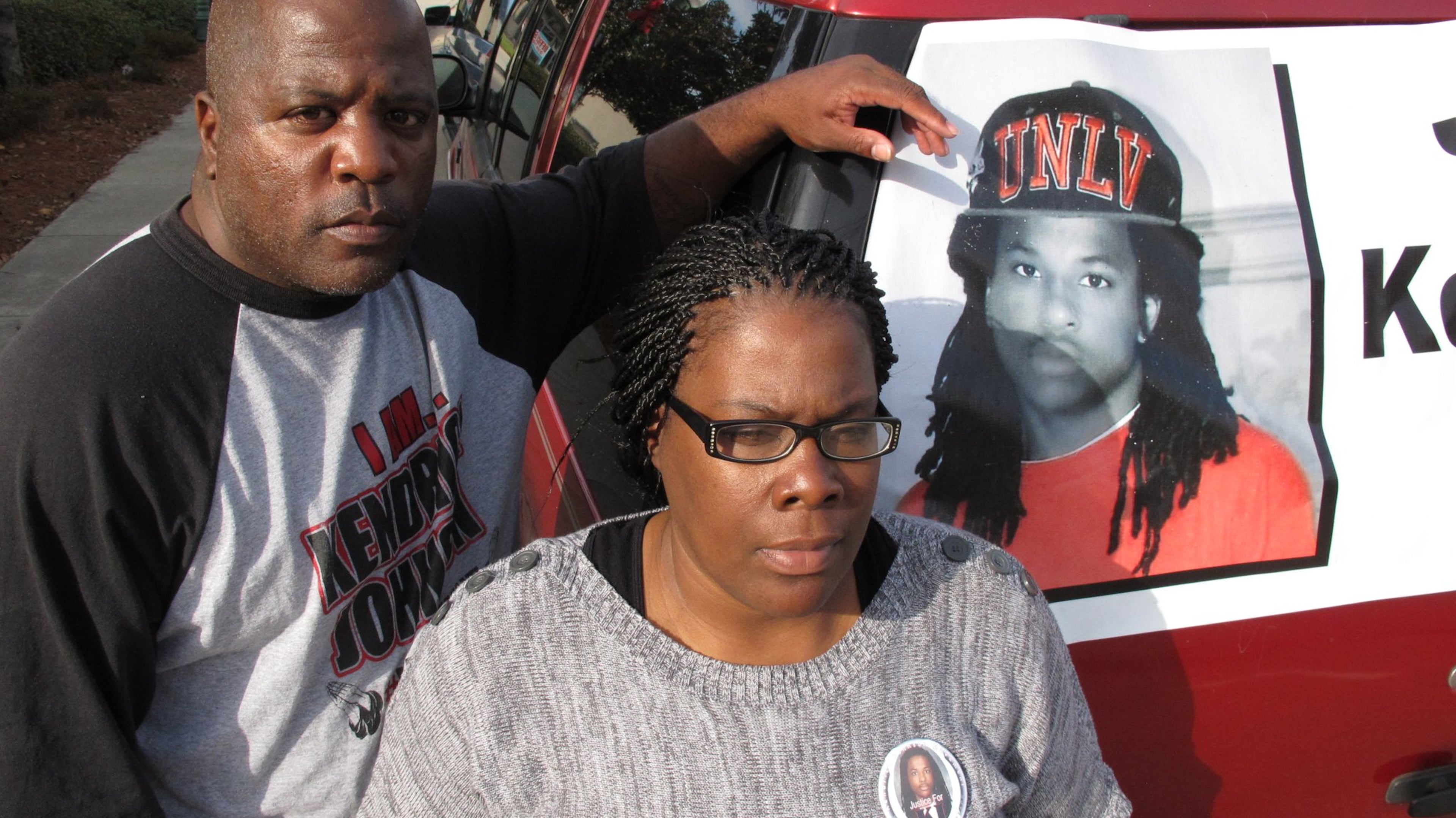 Kenneth and Jacquelyn Johnson stand next to a banner on their SUV showing their late son, Kendrick Johnson, on Dec. 13, 2013, in Valdosta, Ga. The 17 year old was found dead inside a rolled up gym mat at his high school Jan. 11, 2013, and authorities ruled it was a freak accident. Kendrick’s family believes someone killed him and has been fighting to reopen the case. (AP Photo/Russ Bynum)