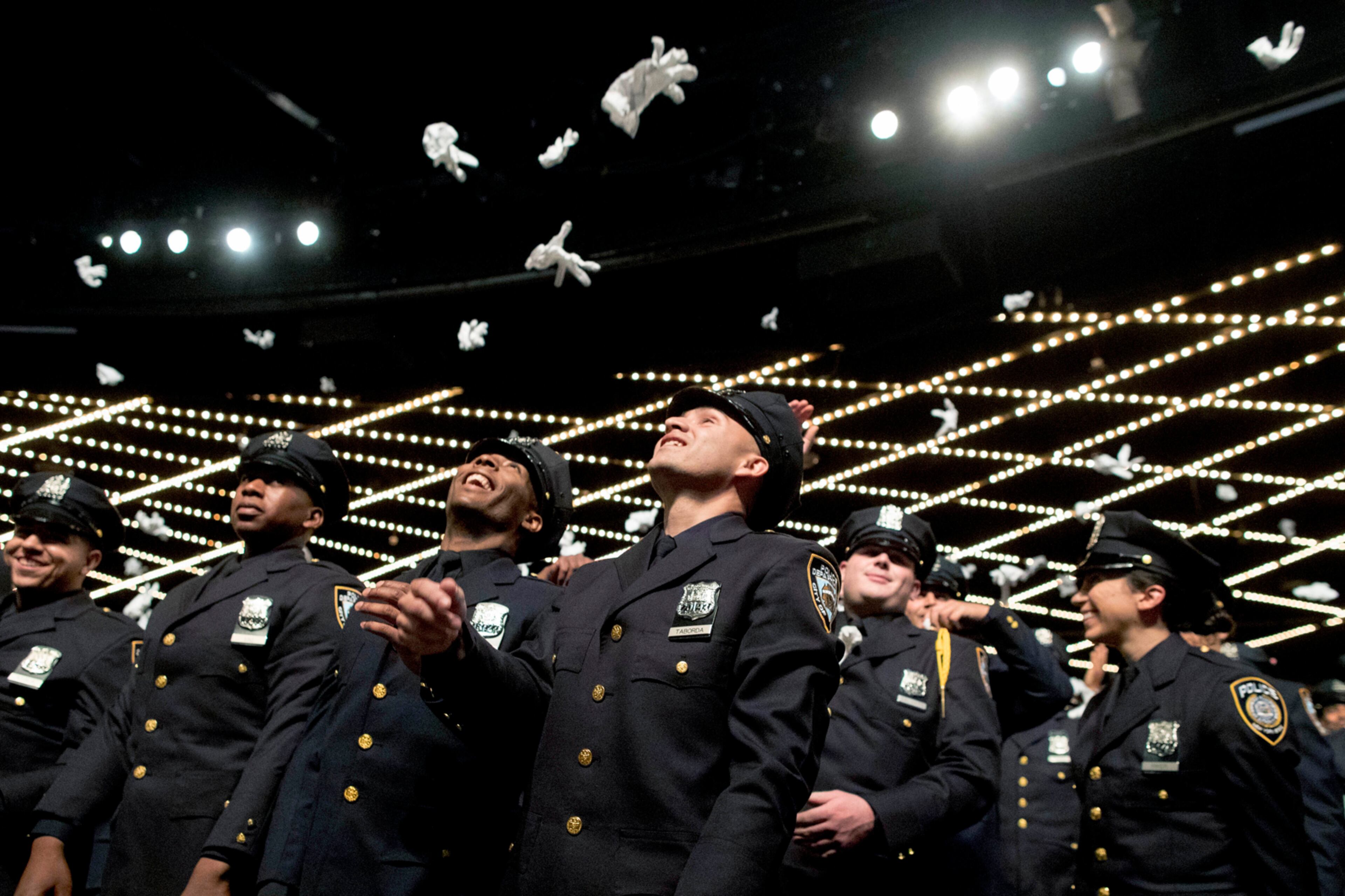 The newest members of the New York City police toss their gloves into the air during their graduation ceremony, Thursday, June 29, 2017, in New York. Over 400 men and women took the oath of office and pledged to protect the people of New York City in a ceremony held at the Madison Square Garden Theatre. (AP Photo/Mary Altaffer)