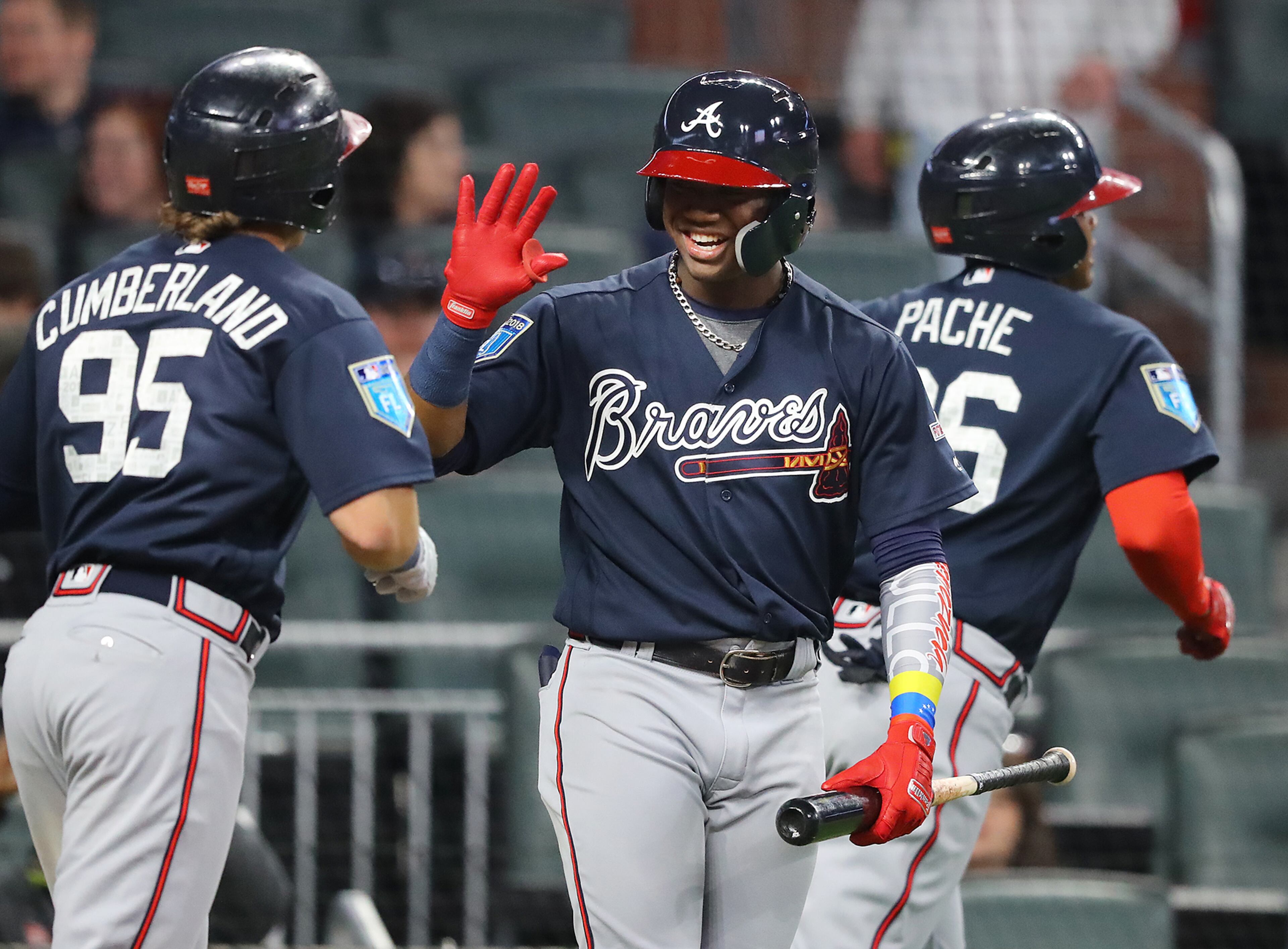 March 27, 2018 Atlanta: Braves Ronald Acuna Jr. gives outfielder Cristian Pache (right) and Brett Cumberland (left) high fives at homeplate after Pache hit a 2-run homer off pitcher Sean Newcomb to tie the game 2-2 during the third inning in the Future Stars Exhibition Game on Tuesday, March 27, 2018, at SunTrust Park in Atlanta. Curtis Compton/ccompton@ajc.com