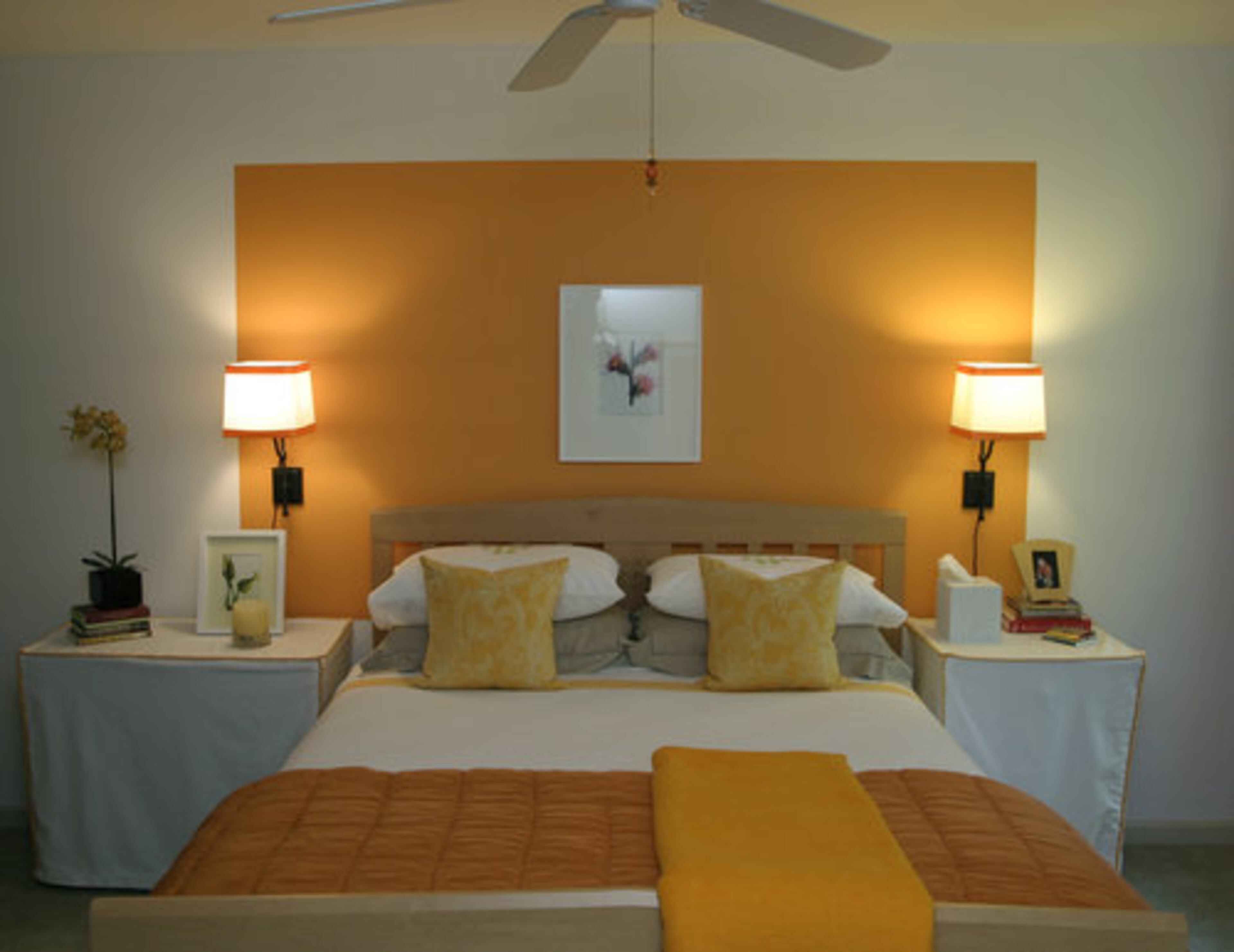 The use of bright oranges and yellows invigorate the guest bedroom. The print above the bed is a weed from a photo book.