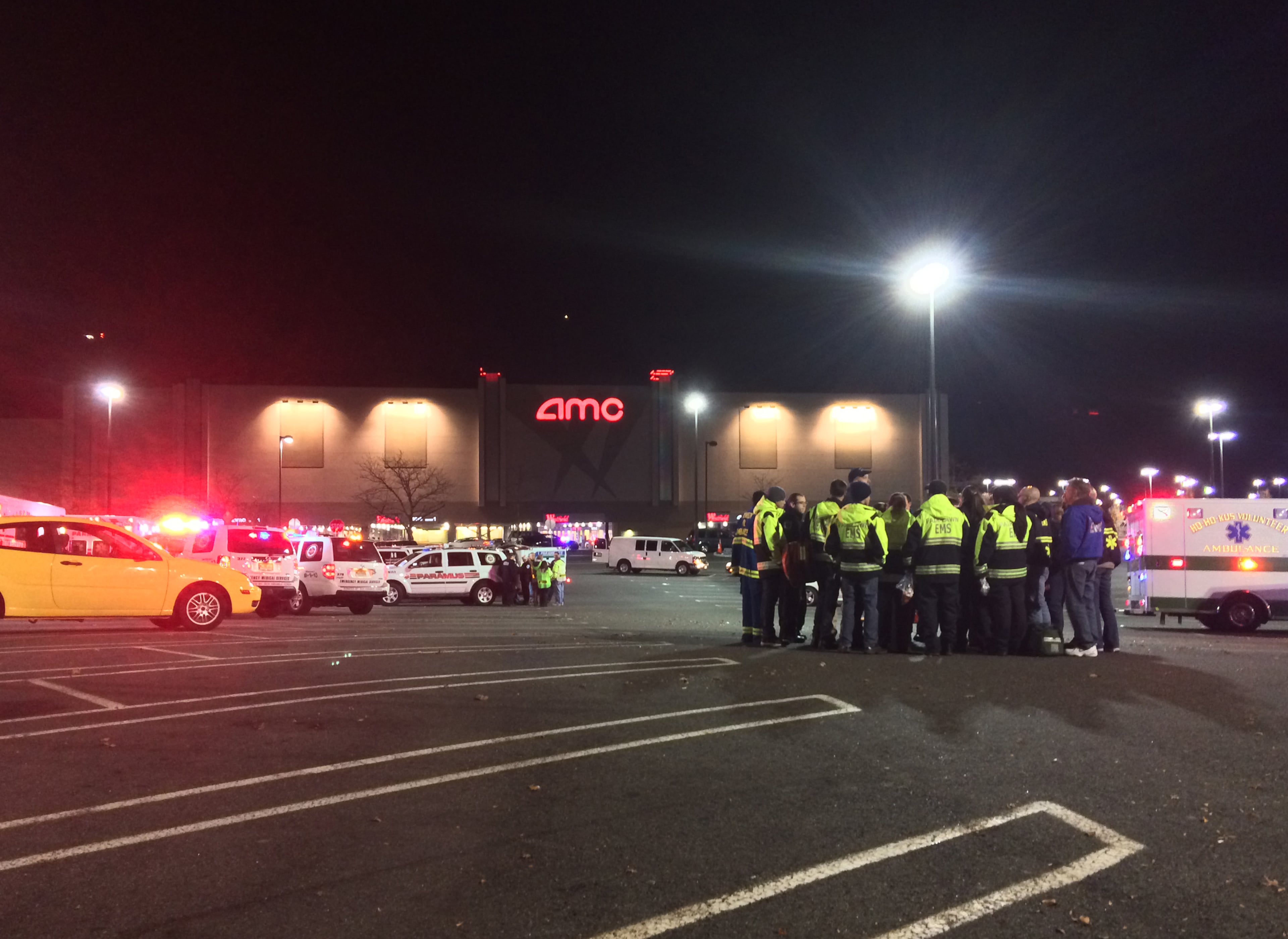 In this photo taken and provided to the AP, which has been authenticated based on its contents and other AP reporting, authorities stand in the parking lot of Garden State Plaza Mall, late Monday, Nov. 4, 2013, in Paramus, N.J., after there were reports of multiple shots being fired inside the mall. (AP Photo/Carlos Sinde)