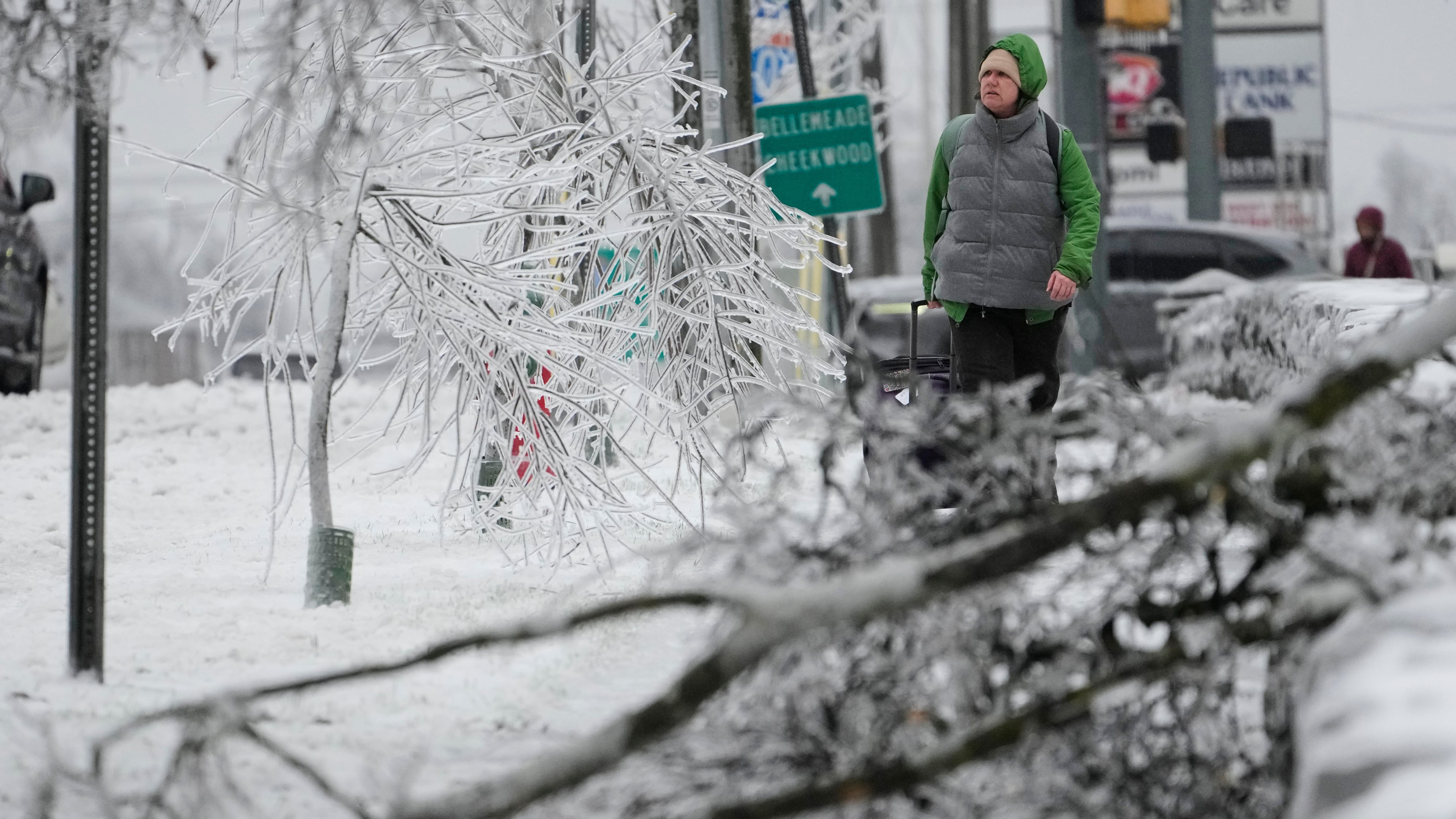 A person walks past ice covered trees and a fallen limb during a winter storm Sunday, Jan. 25, 2026, in Nashville, Tenn. (AP Photo/George Walker IV)