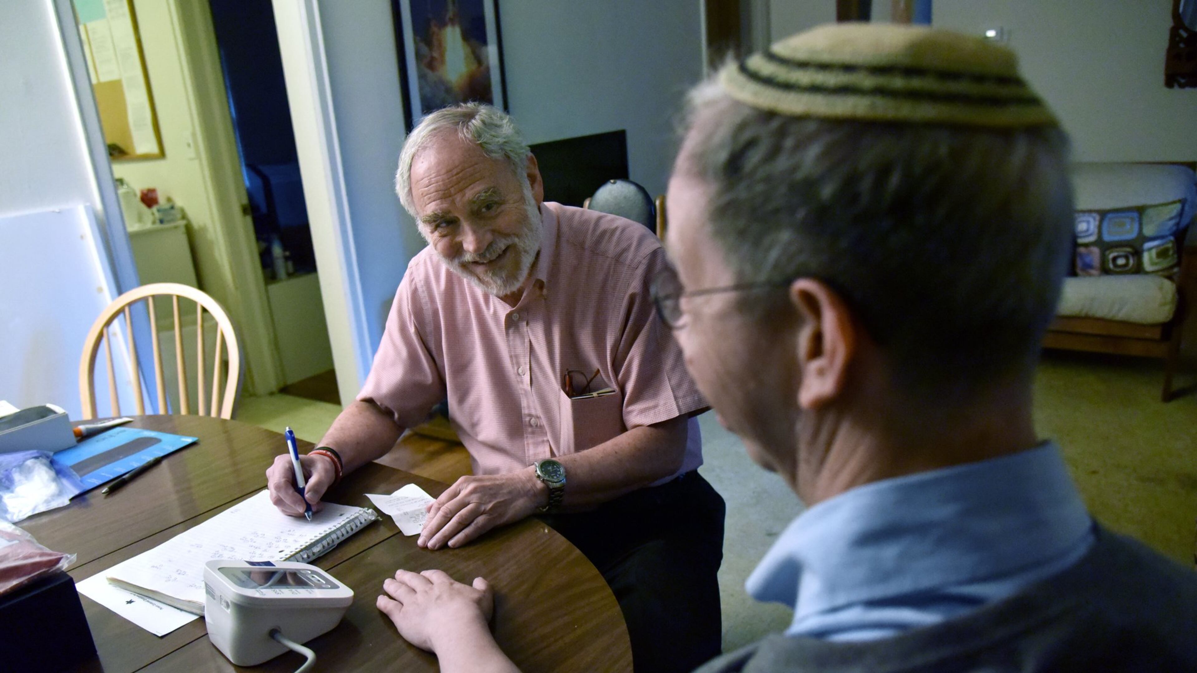 June 29, 2017 Atlanta - Sandy Hartman takes a note after he took a blood pressure of his son Aaron Hartman, who has Williams Syndrome, using a blood pressure device that was purchased through Medicaid at Aaron’s home on Thursday, June 29, 2017. Aaron Hartman, who has Williams Syndrome, has Medicaid-funded services that have helped him get and keep a job working a couple hours at Publix a couple days a week. HYOSUB SHIN / HSHIN@AJC.COM
